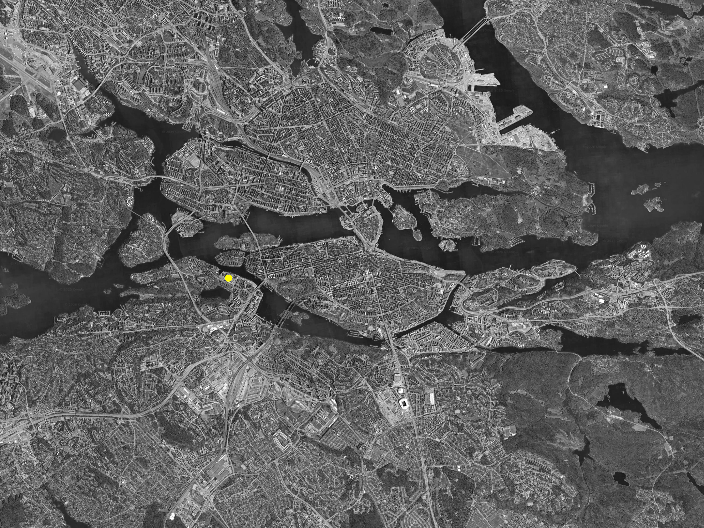 High-angle view of a city with waterways, bridges, roads, and densely built areas in grayscale.