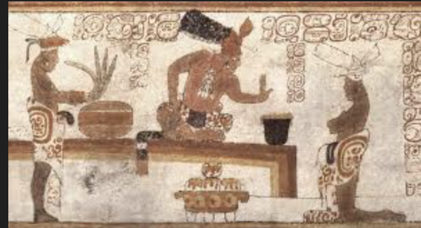 Ancient Mesoamerican mural showing three figures, one at the center sitting and gesturing, with two figures on either side, one holding a basket and the other with a feathered headdress, in a colorful decorative style.