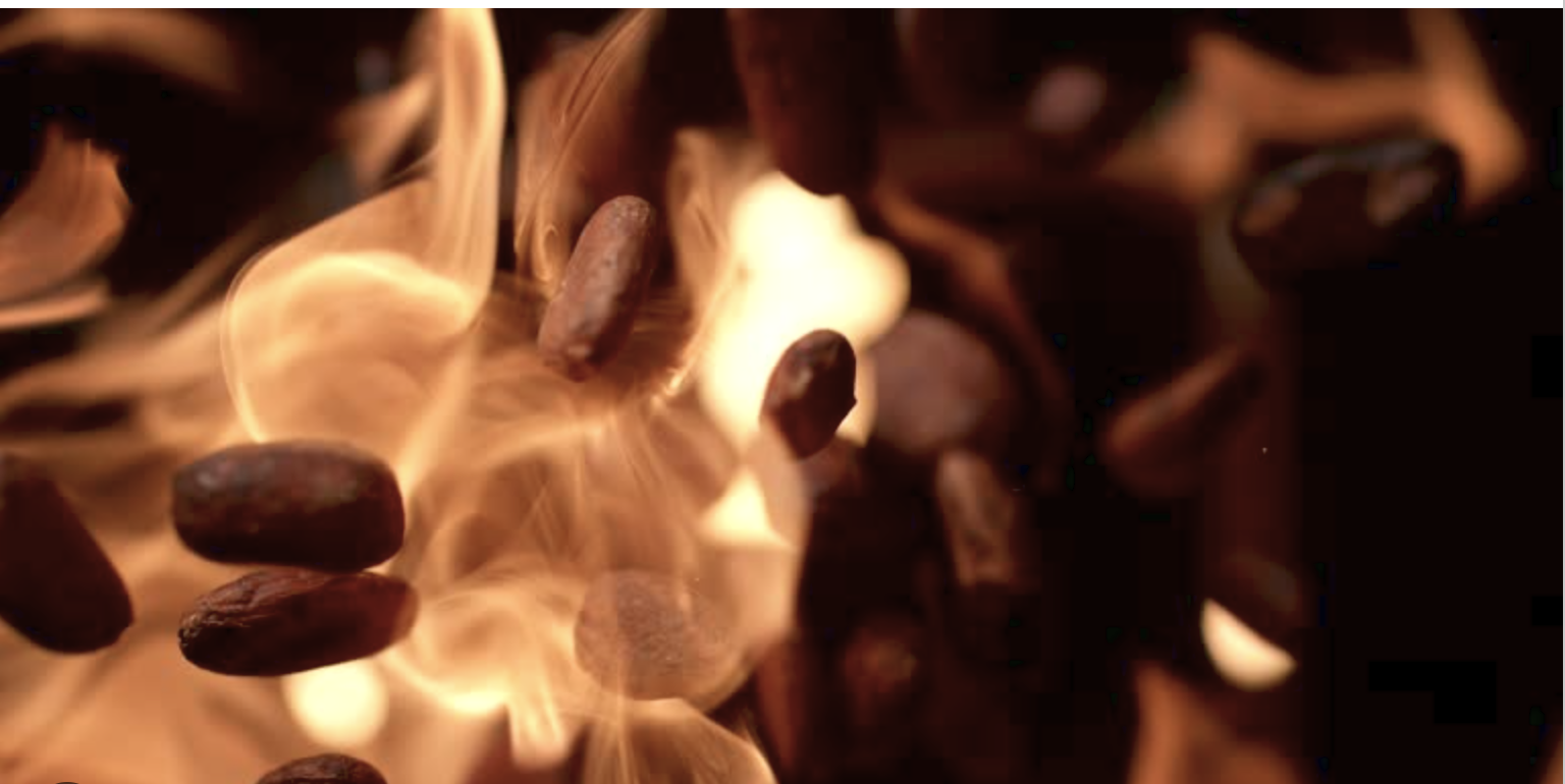 Close-up of burning coffee beans with flames and smoke.