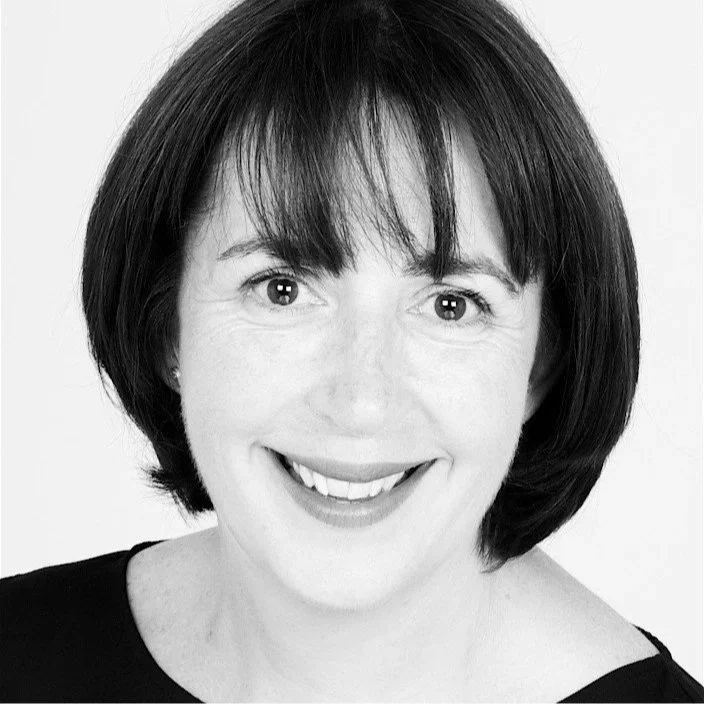 Black and white photo of a woman with short hair smiling with her teeth showing.