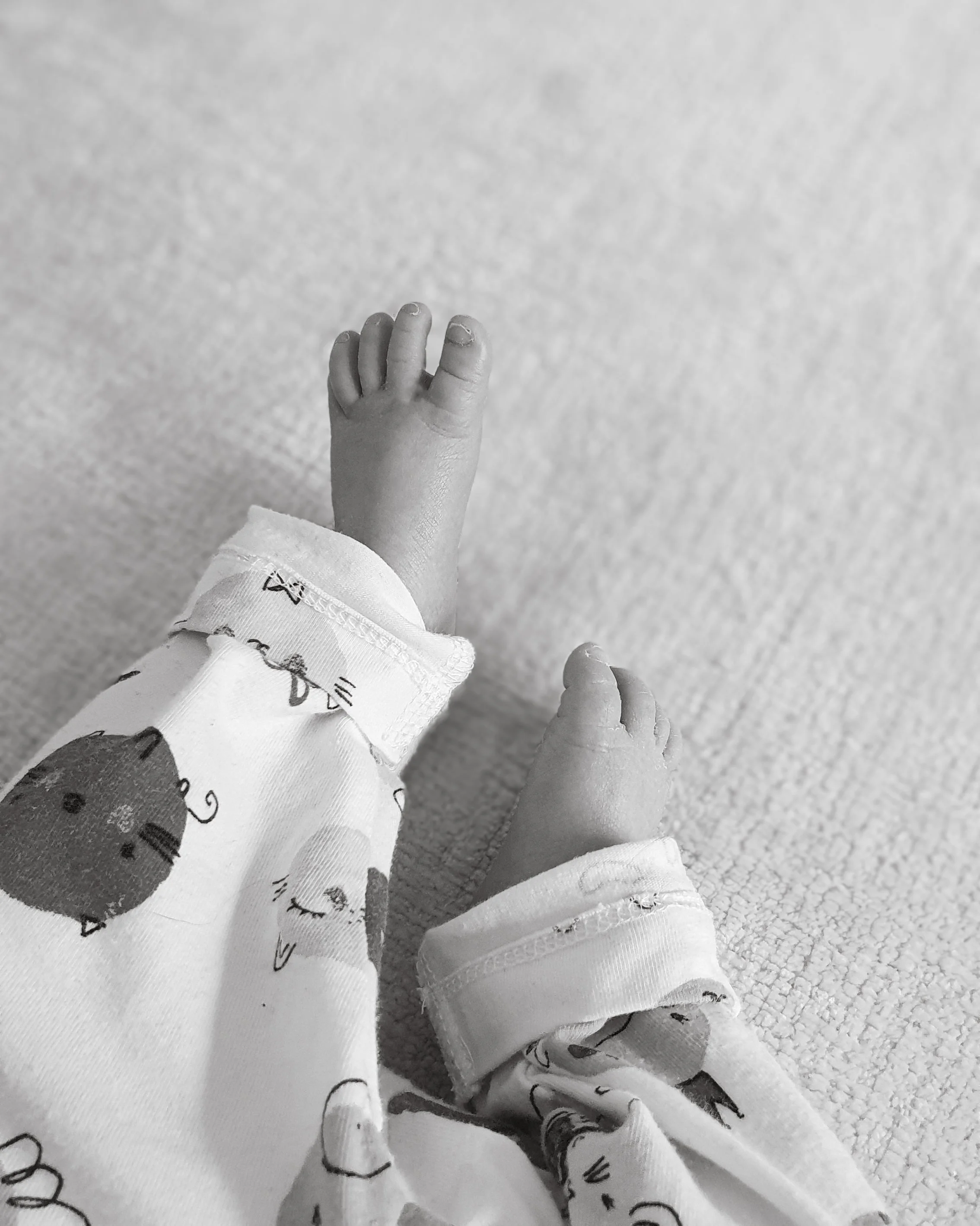 A soft, unscripted in-home newborn photography detail of a baby's legs on the sofa, by a Surrey lifestyle family photographer.