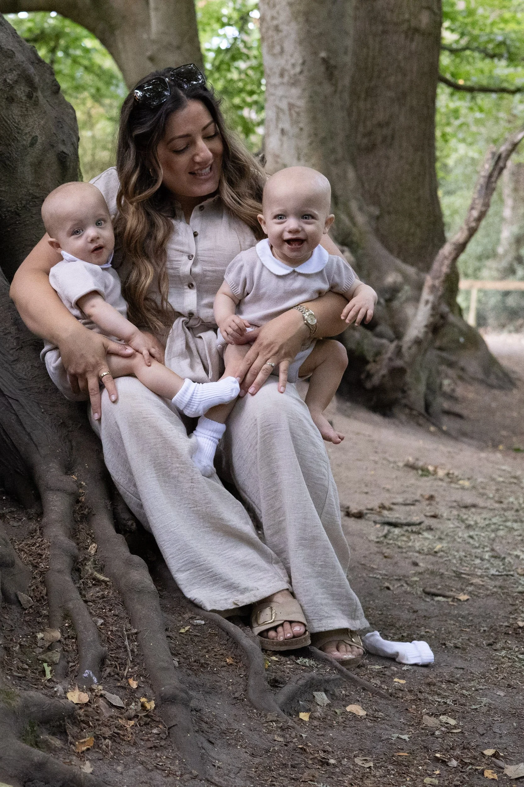 Candid moment with mother holding her twin babies during a photoshoot outdoors,