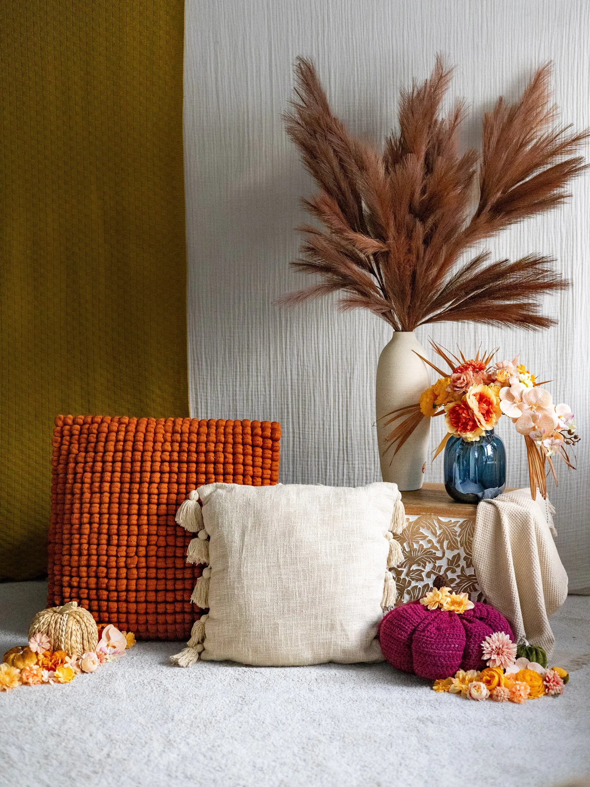 Warm autumn family photography set design featuring mustard and white backdrop fabric, pampas grass, and decorative pumpkins by Laura Rickute Photography in Camberley.