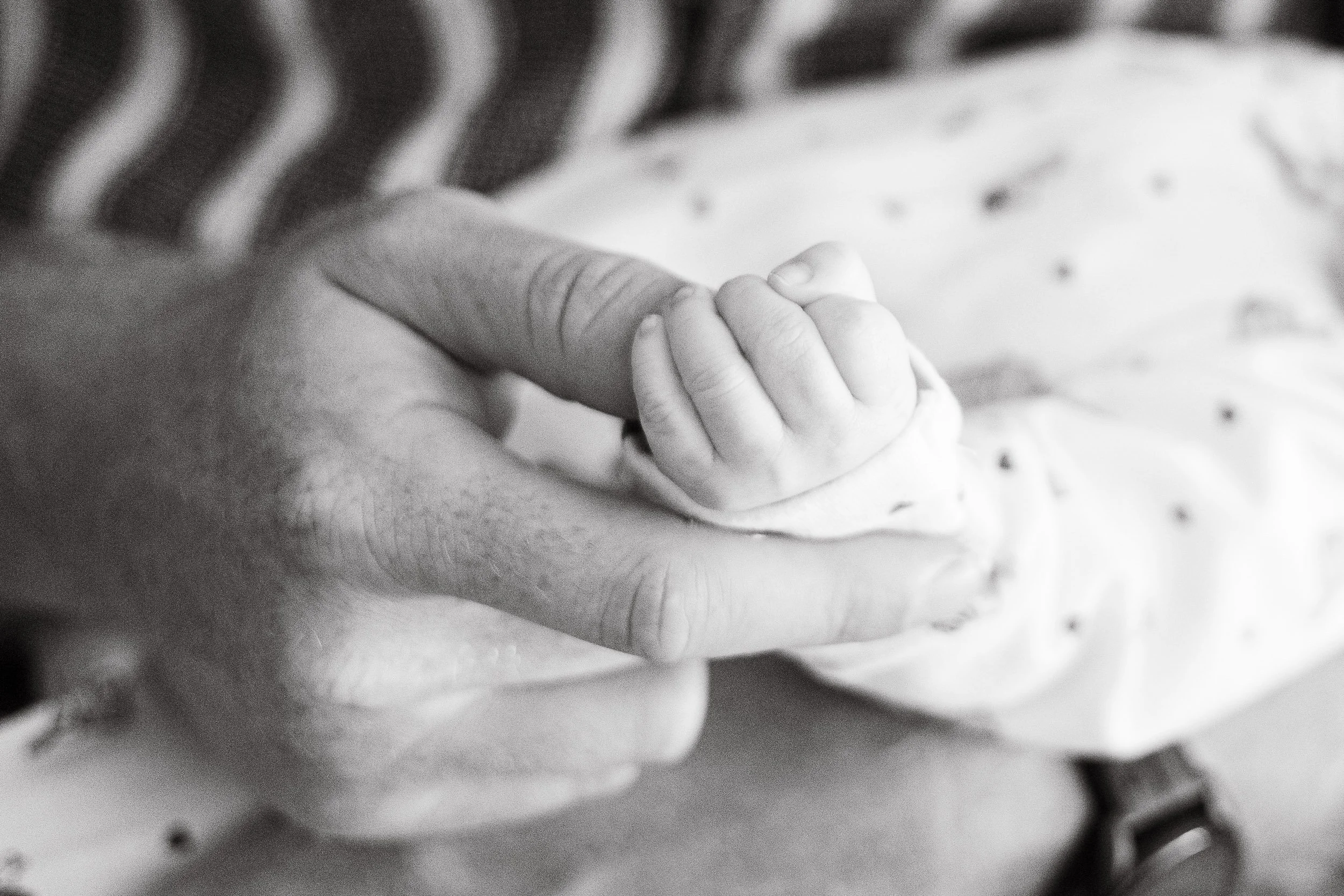 Father holding his baby's hand during newborn photoshoot at home,