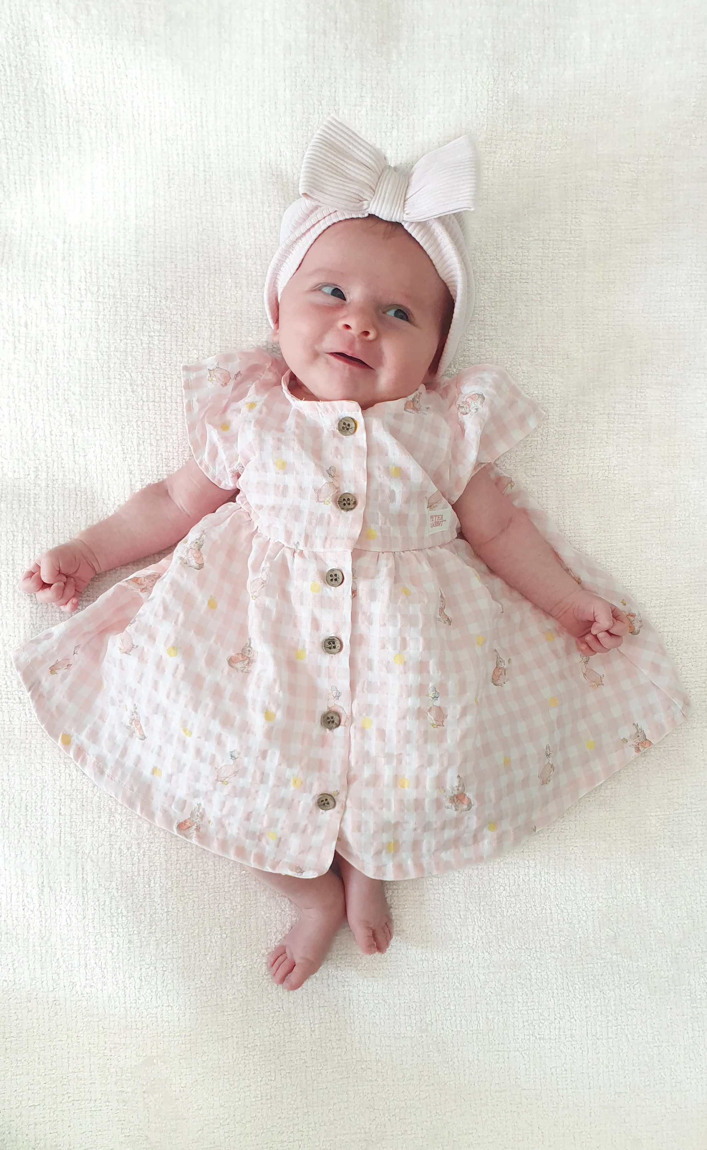 Baby wearing a bow and a cute dress smiling at the parent
