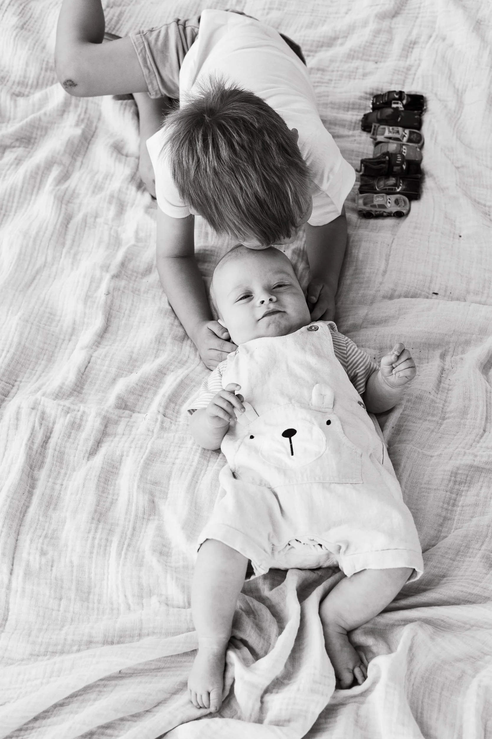 Boy cuddling his baby brother during photoshoot.