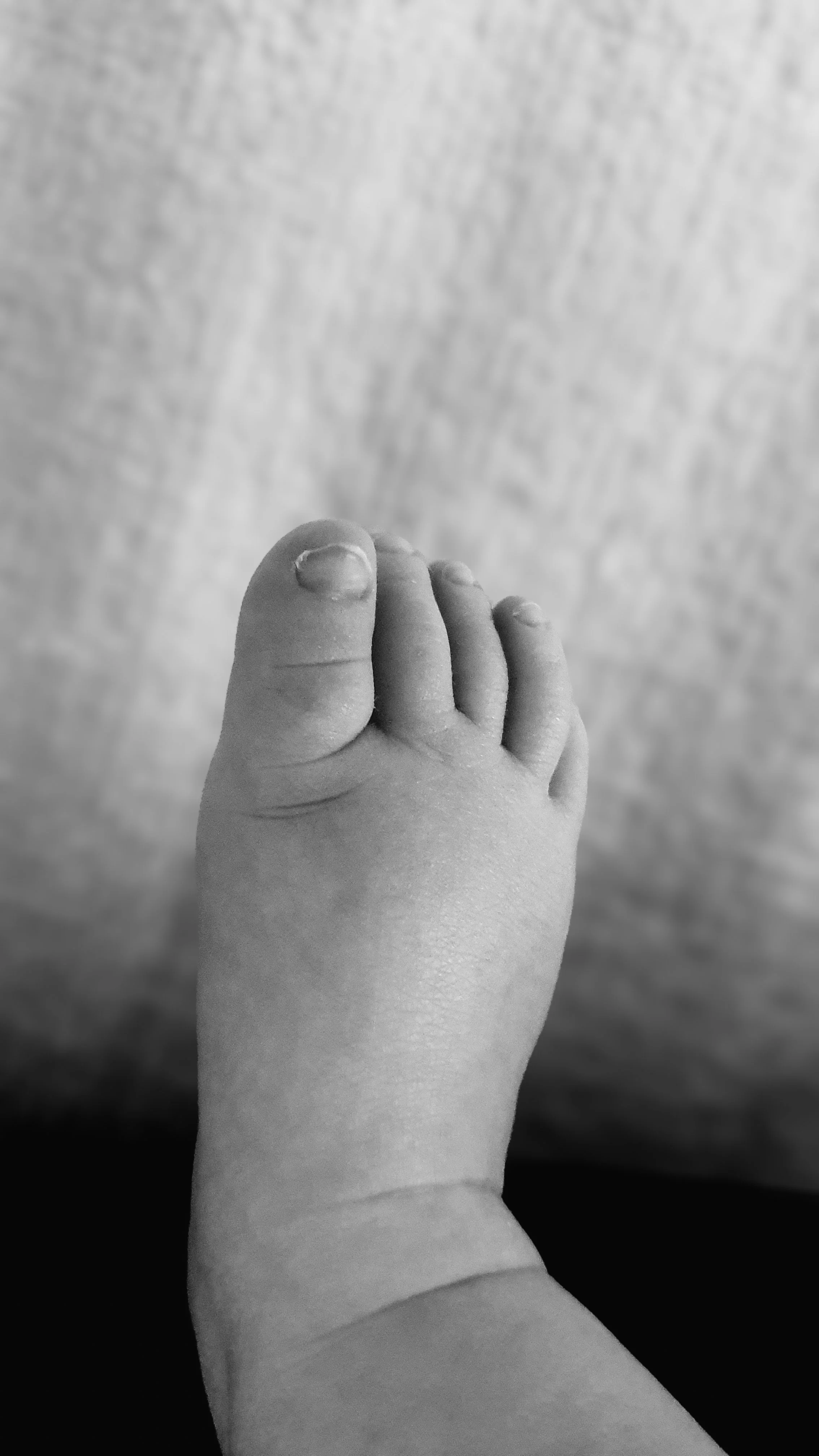 An intimate newborn macro detail shot of a baby's foot.