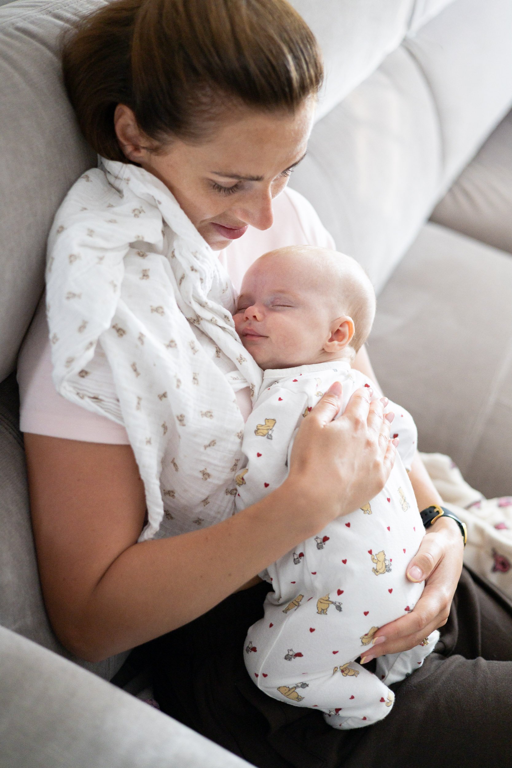 Mother cuddling her baby during in-home newborn photography session in Camberley.