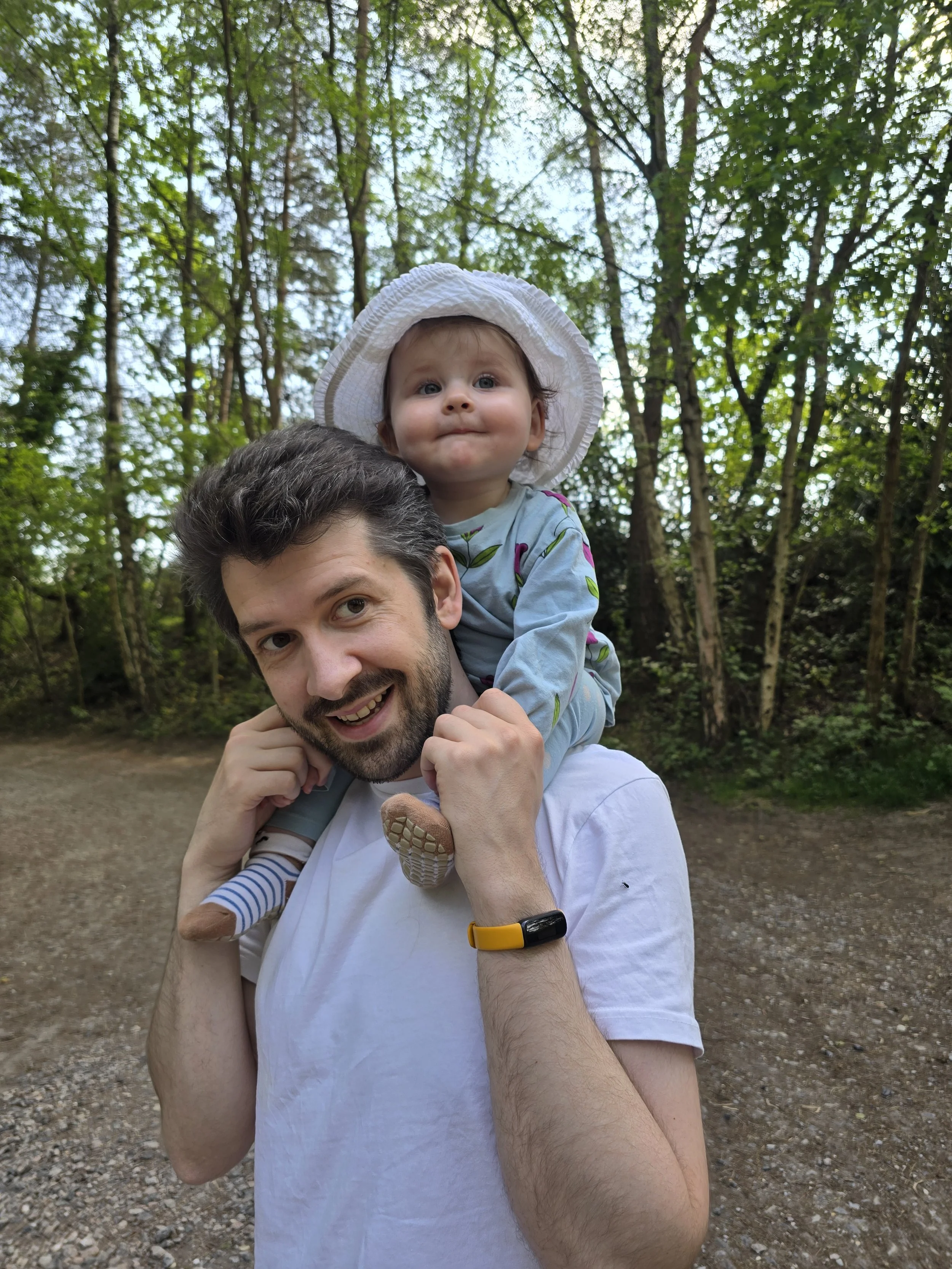 A natural, unscripted lifestyle portrait of a baby sitting on dad's shoulders and smiling, captured by a Lightwater family photographer..