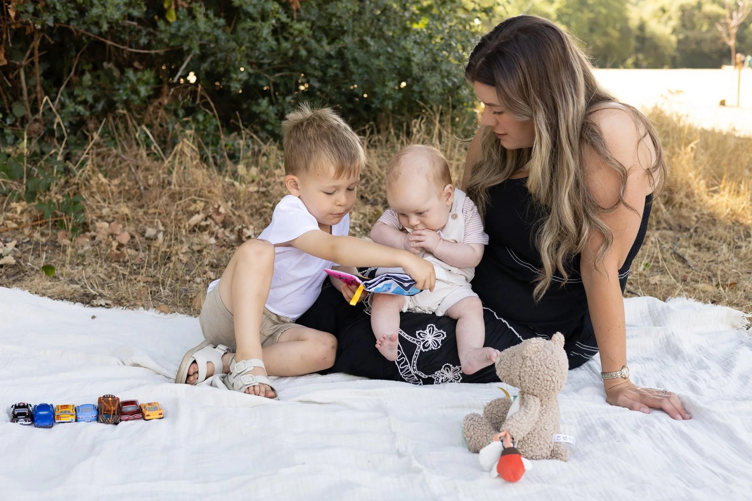 Mother sitting outdoors on blanket with young children and dog during candid family photoshoot in Surrey  Additional Images (3-Style Breakdown Sectio
