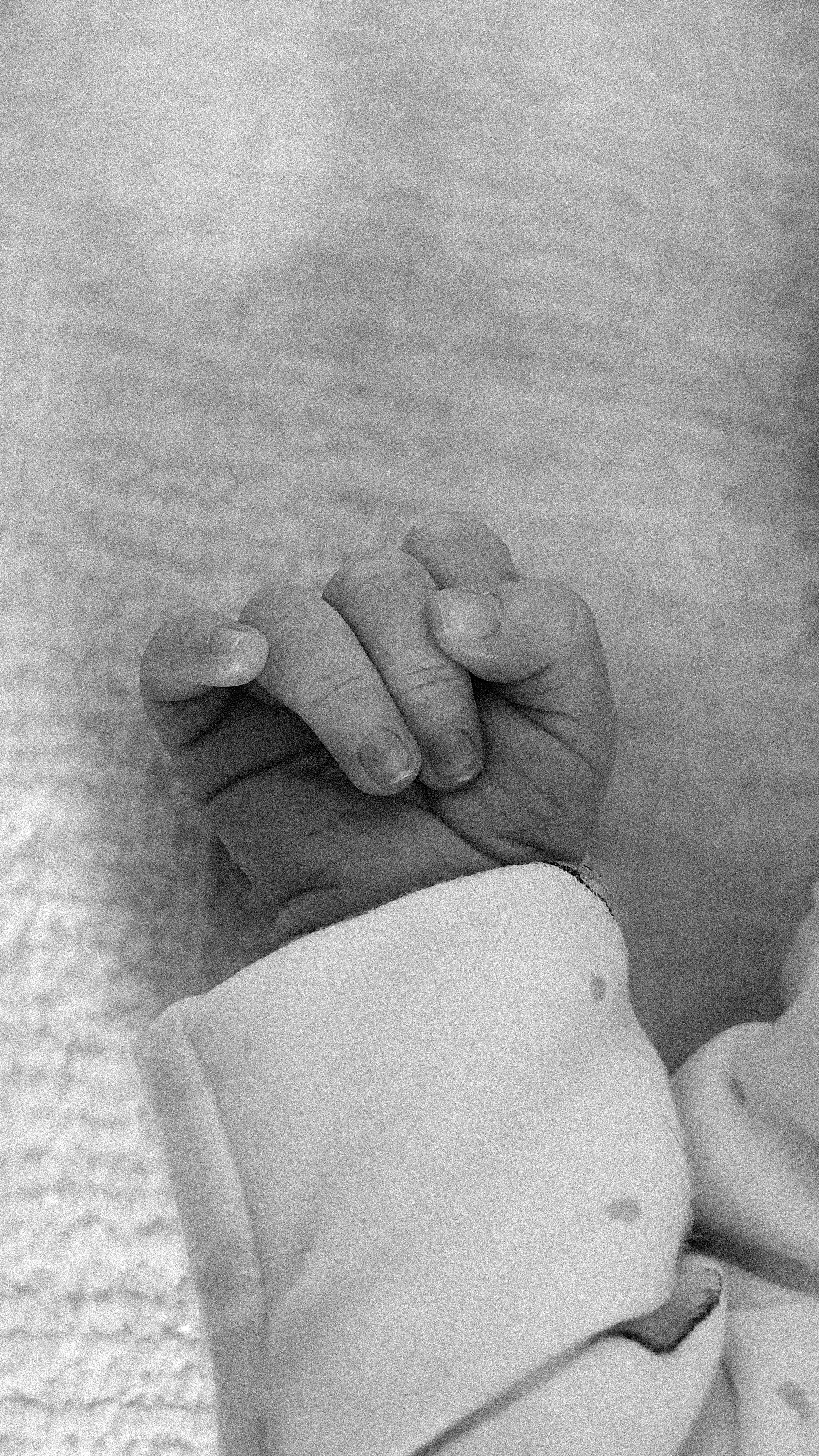 A bright and airy detail portrait focusing on a baby's delicate hand and fingers, showcasing a natural, timeless photography style