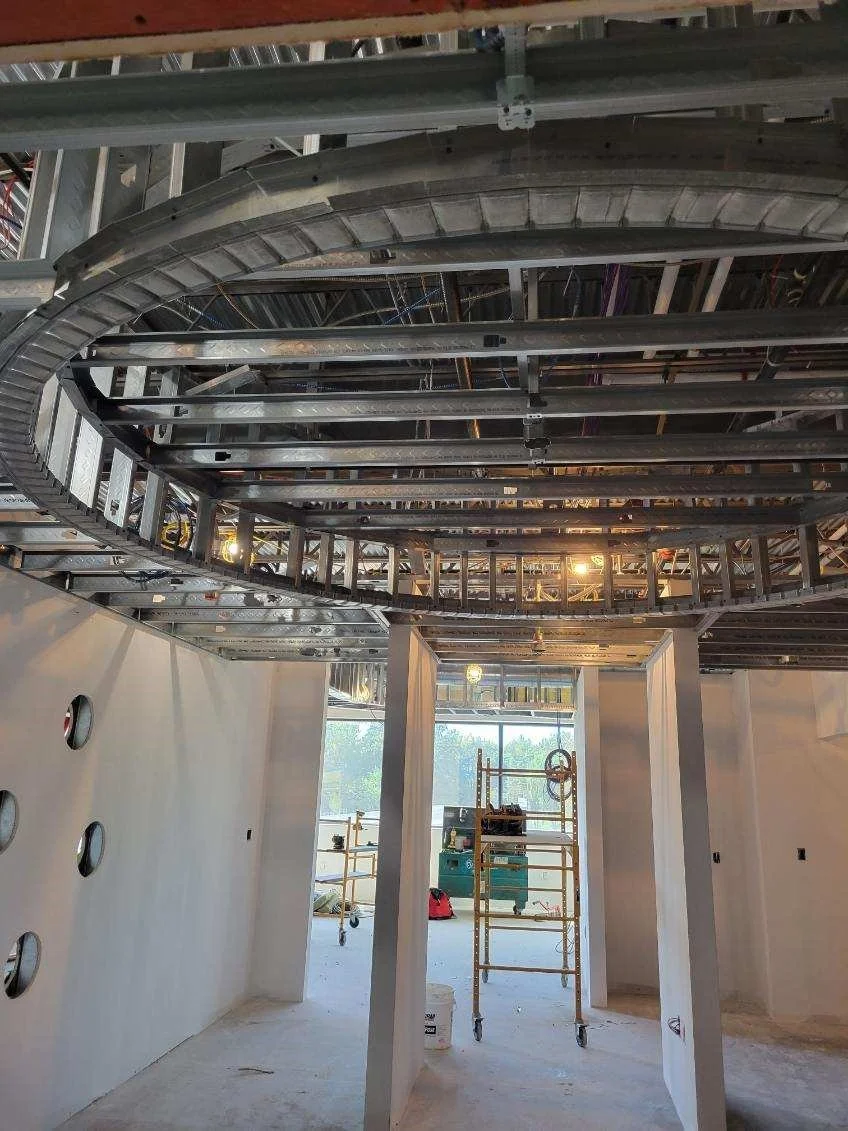 Construction site with exposed metal framework, scaffolding, and unfinished walls inside a building.