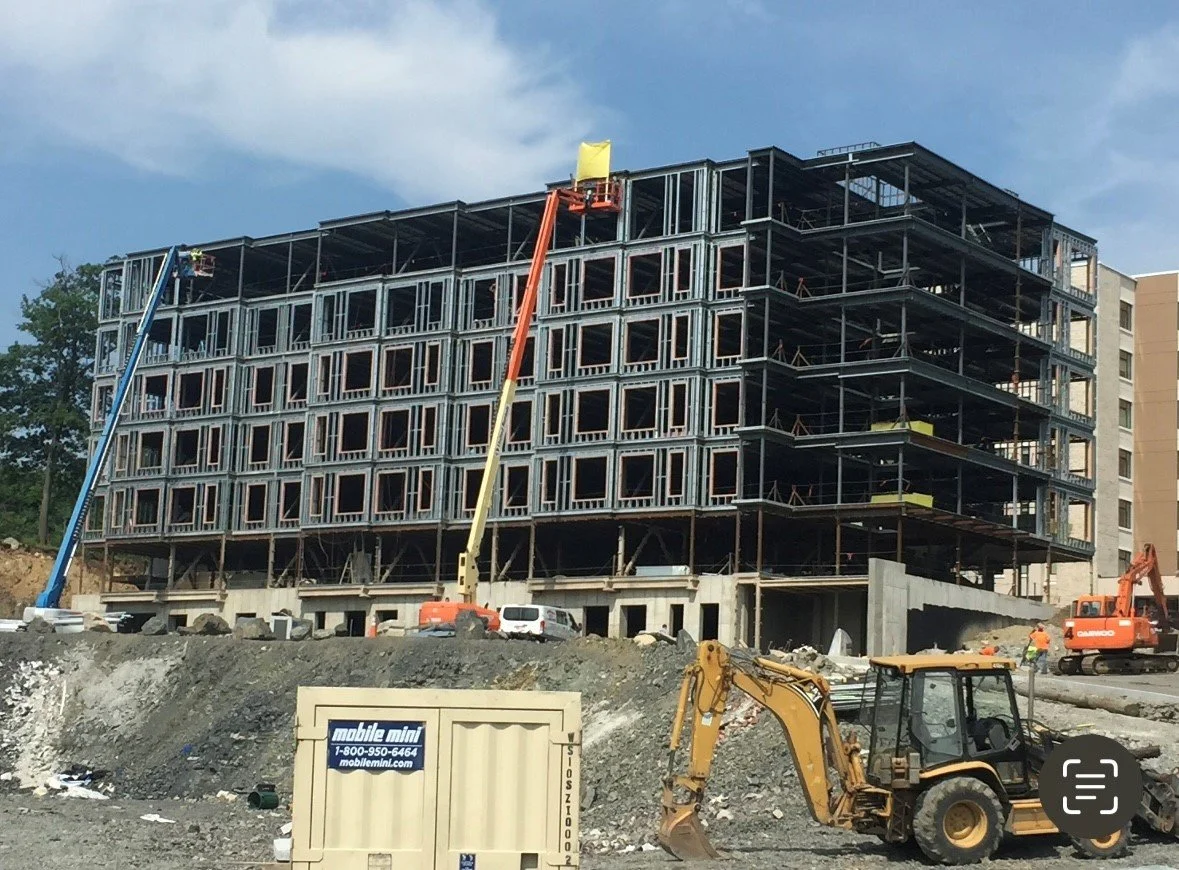 Construction site with a multi-story building under construction, construction vehicles, and workers.