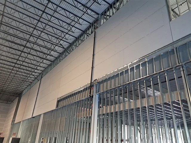 	
Two story interior framing on scissor lift, half the wall with hung drywall.