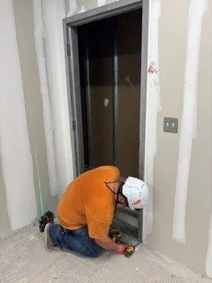 Worker installing a hallow metal door frame.