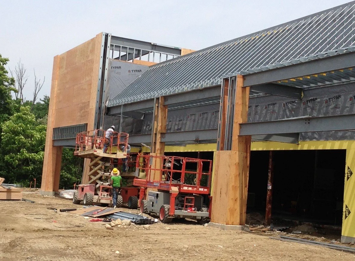 Construction workers using lifts to build a building, with wood and metal framing in progress.