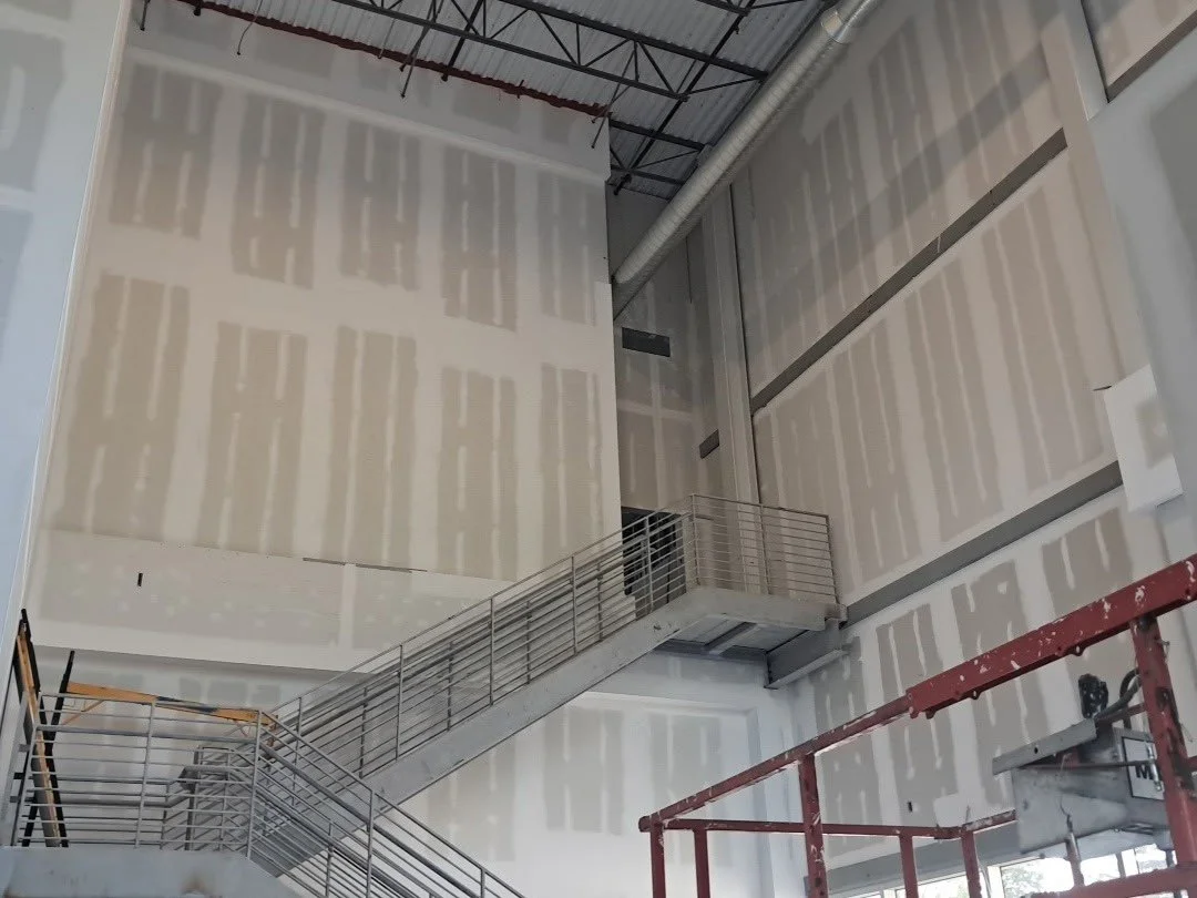 Interior of a building under construction, drywall level 4 finish taped at staircase demising wall.