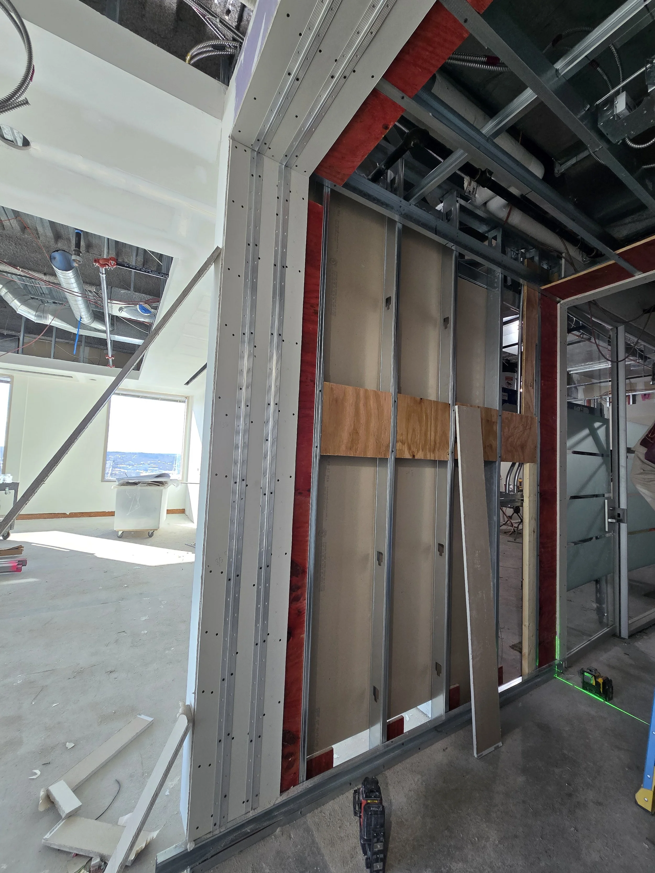 Constructing interior wall with metal framing, insulation, and electrical wiring inside a building under construction.