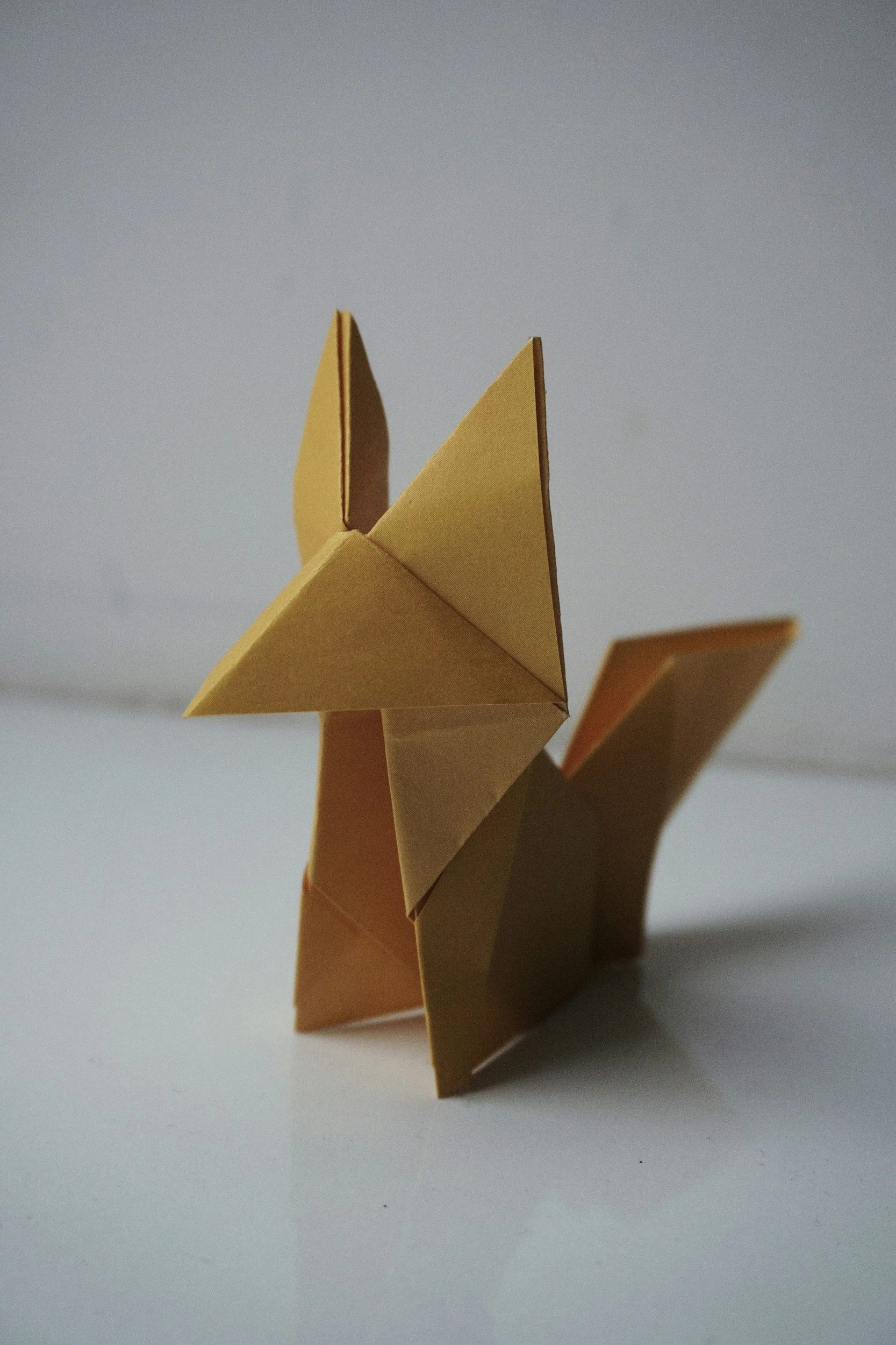 Yellow origami butterfly resting on a reflective surface representing transformation and new possibilities.