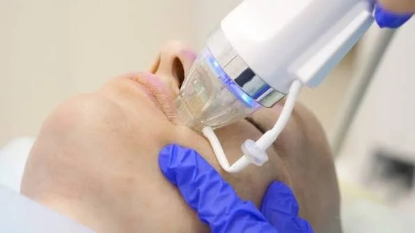 A person receiving a dental or medical treatment with a breathing mask and a gloved hand clearly shown.