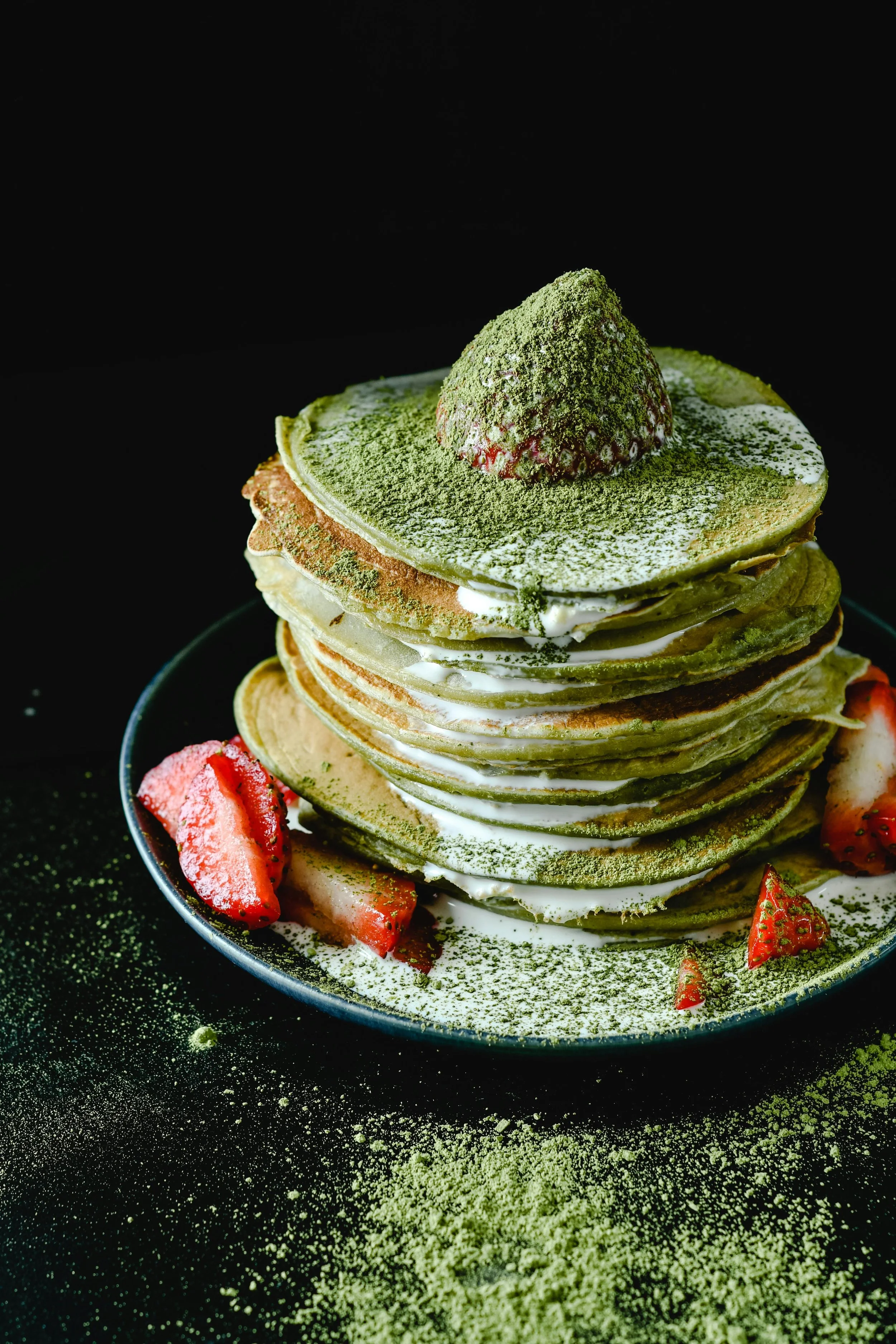 Hoher Stapel Matcha-Pancakes mit Sahne und Erdbeeren