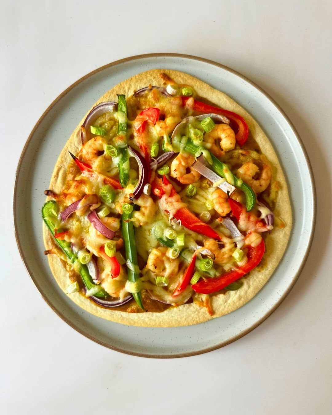 Shrimp and vegetable pizza on a light-colored plate