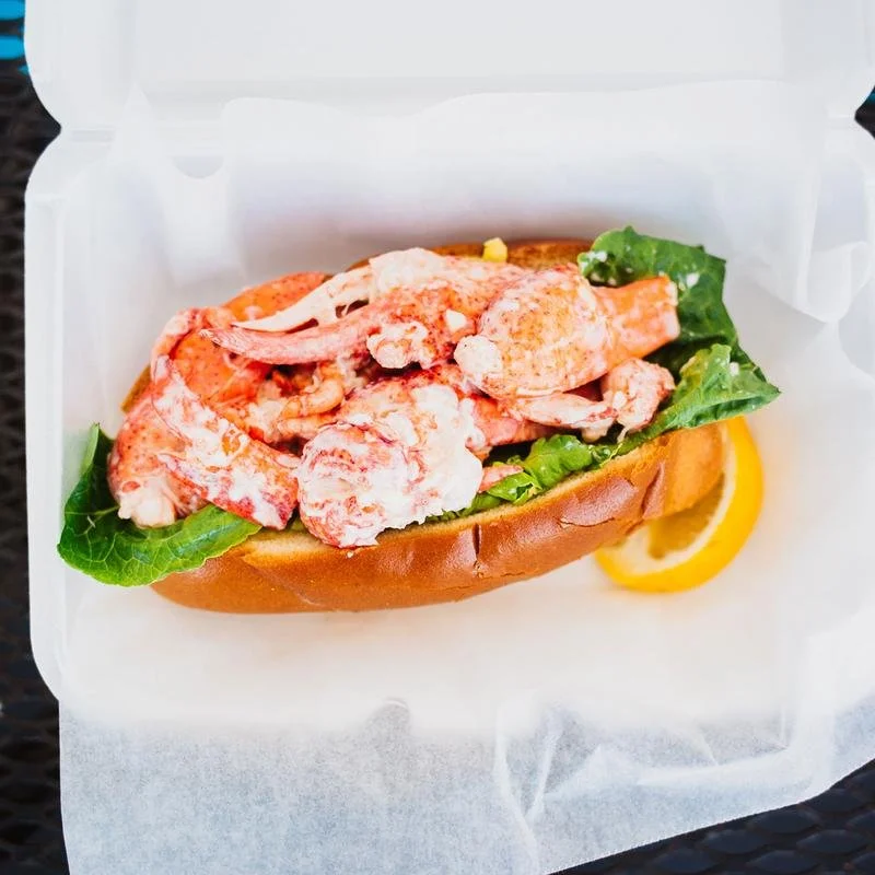 Lobster roll with lettuce and lemon slice in a paper box
