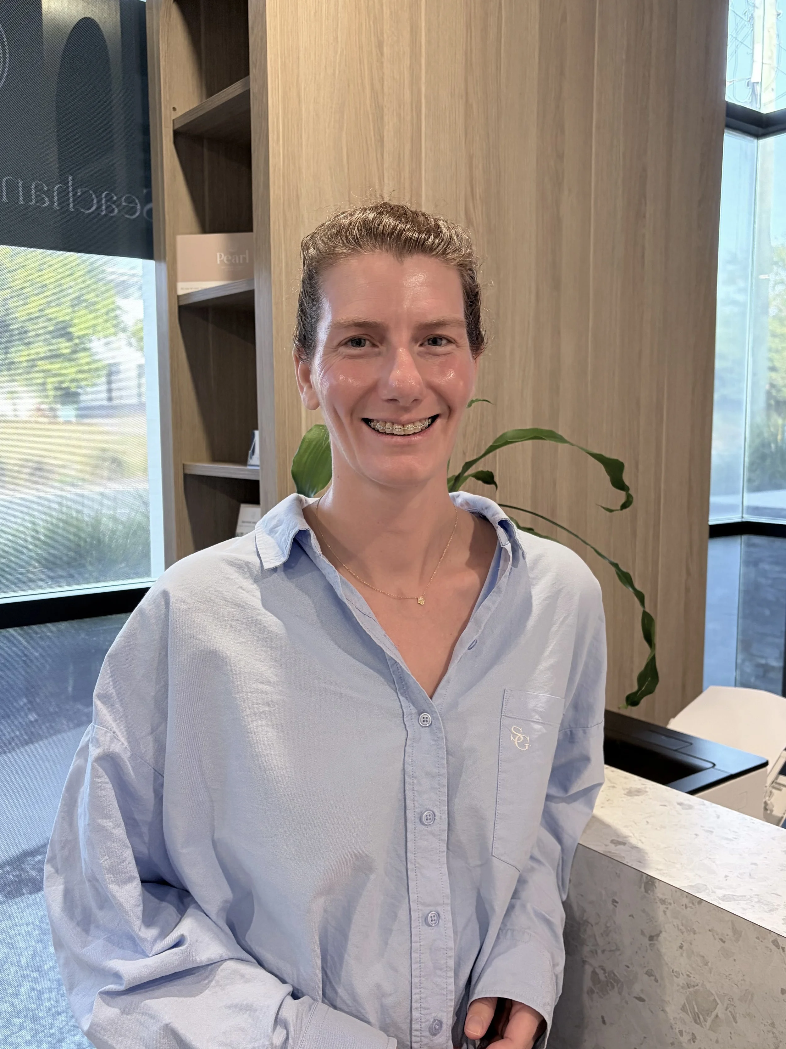 Portrait photo of podiatrist Sarah Mewburn of Peregian Foot Clinic standing at desk smiling at camera.