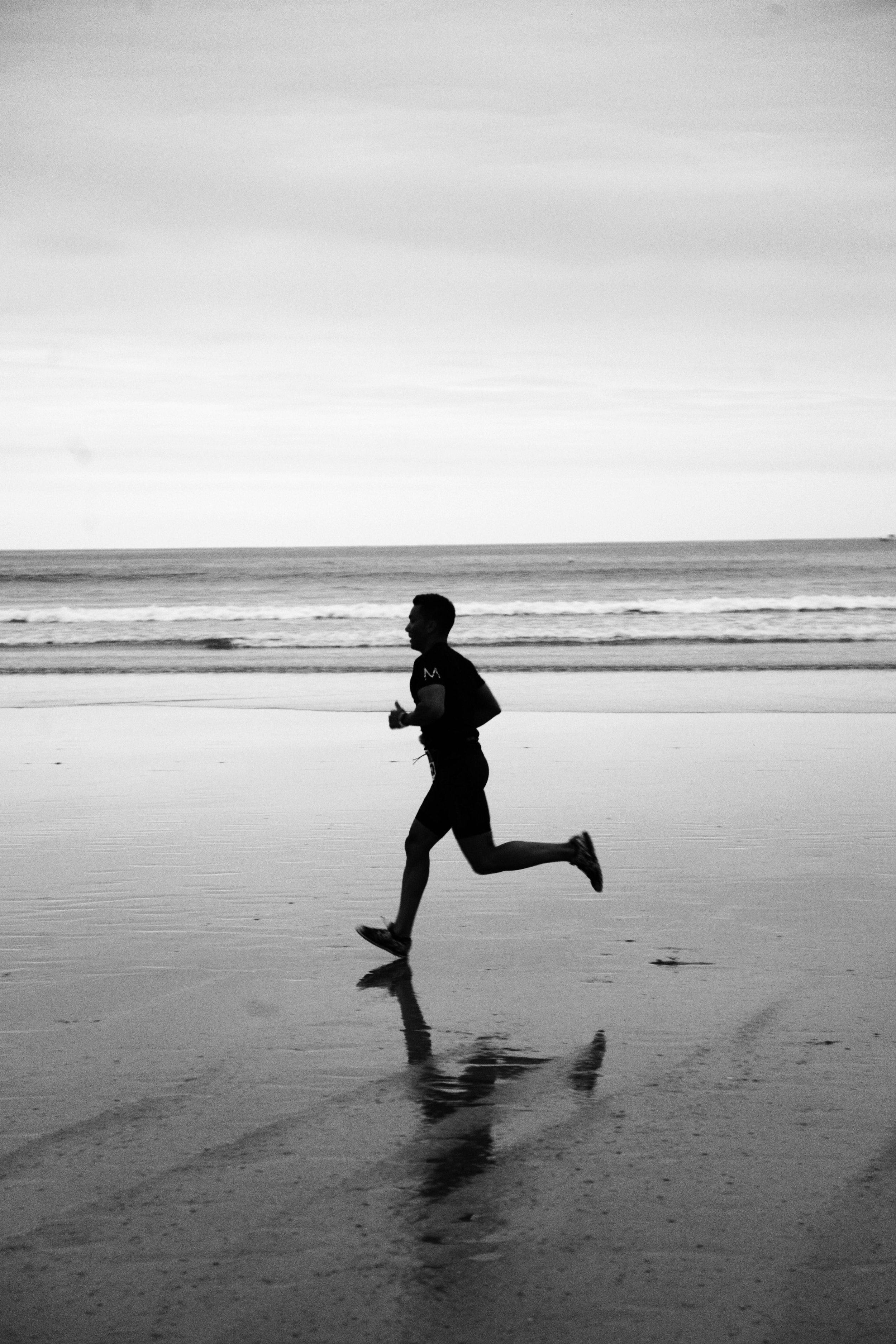 Man running on the Peregian Beach in a black and white high contrast photo