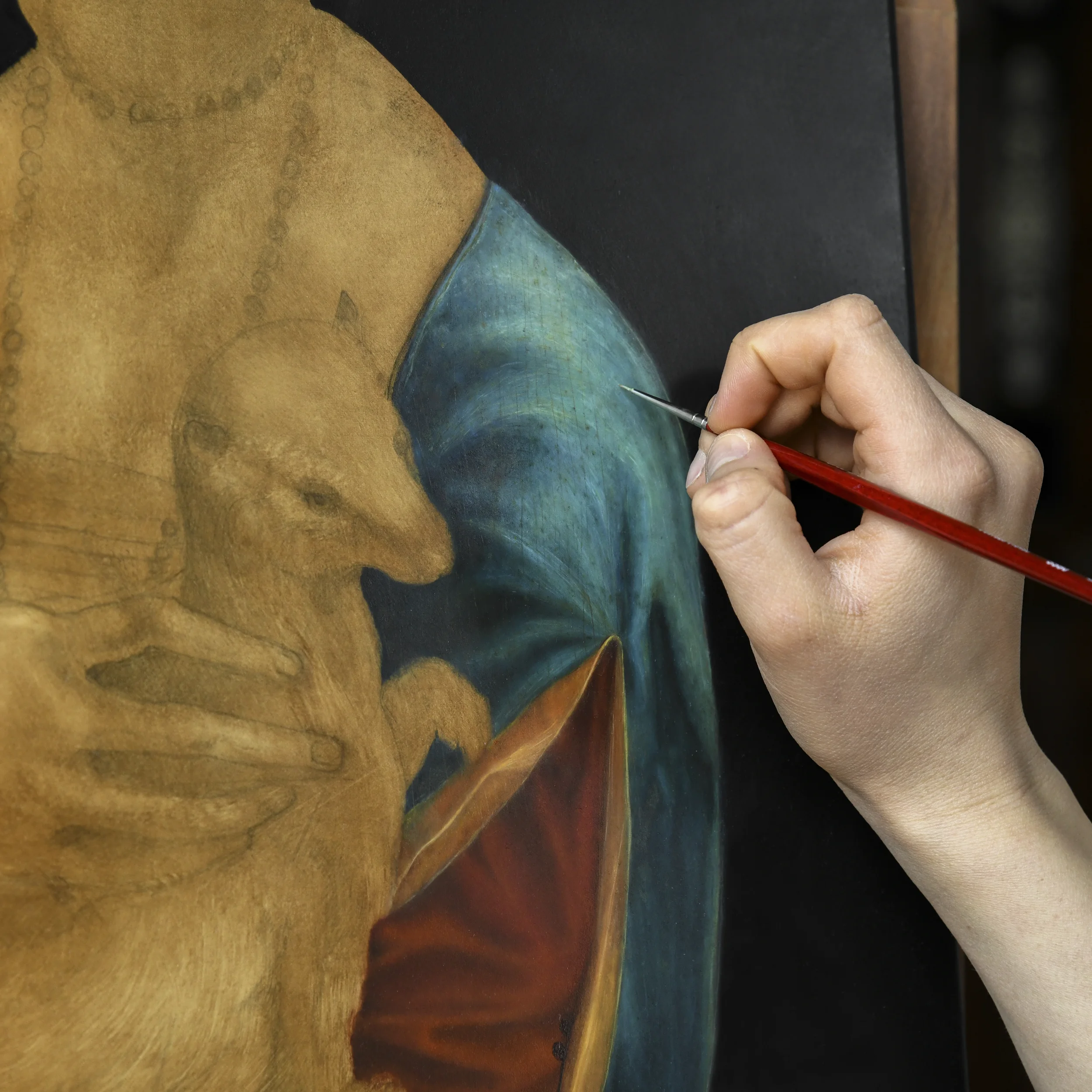 A close-up of the hand of Anna Sumislawska painting a copy of Lady with an Ermine after Leonardo da Vinci in oil on canvas. The image shows the work in progress. 