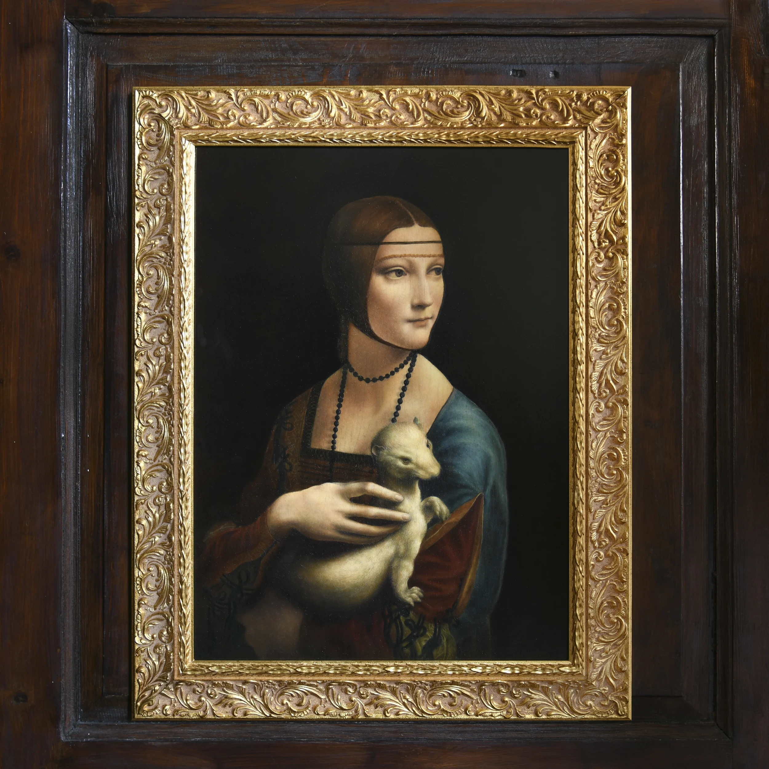 Finished oil painting copy of Lady with an Ermine after Leonardo da Vinci by Anna Sumislawska, featuring a woman holding a small ermine, displayed in an ornate gold frame on a dark wooden background. 