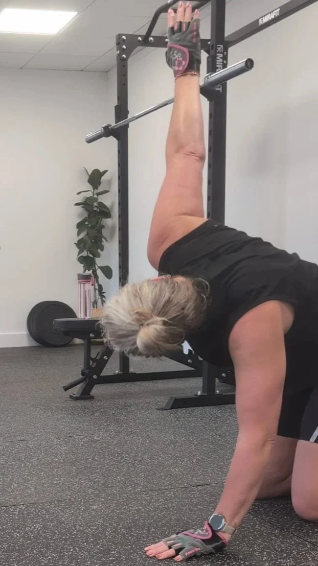 A woman in workout gloves is doing a one-armed weight lift