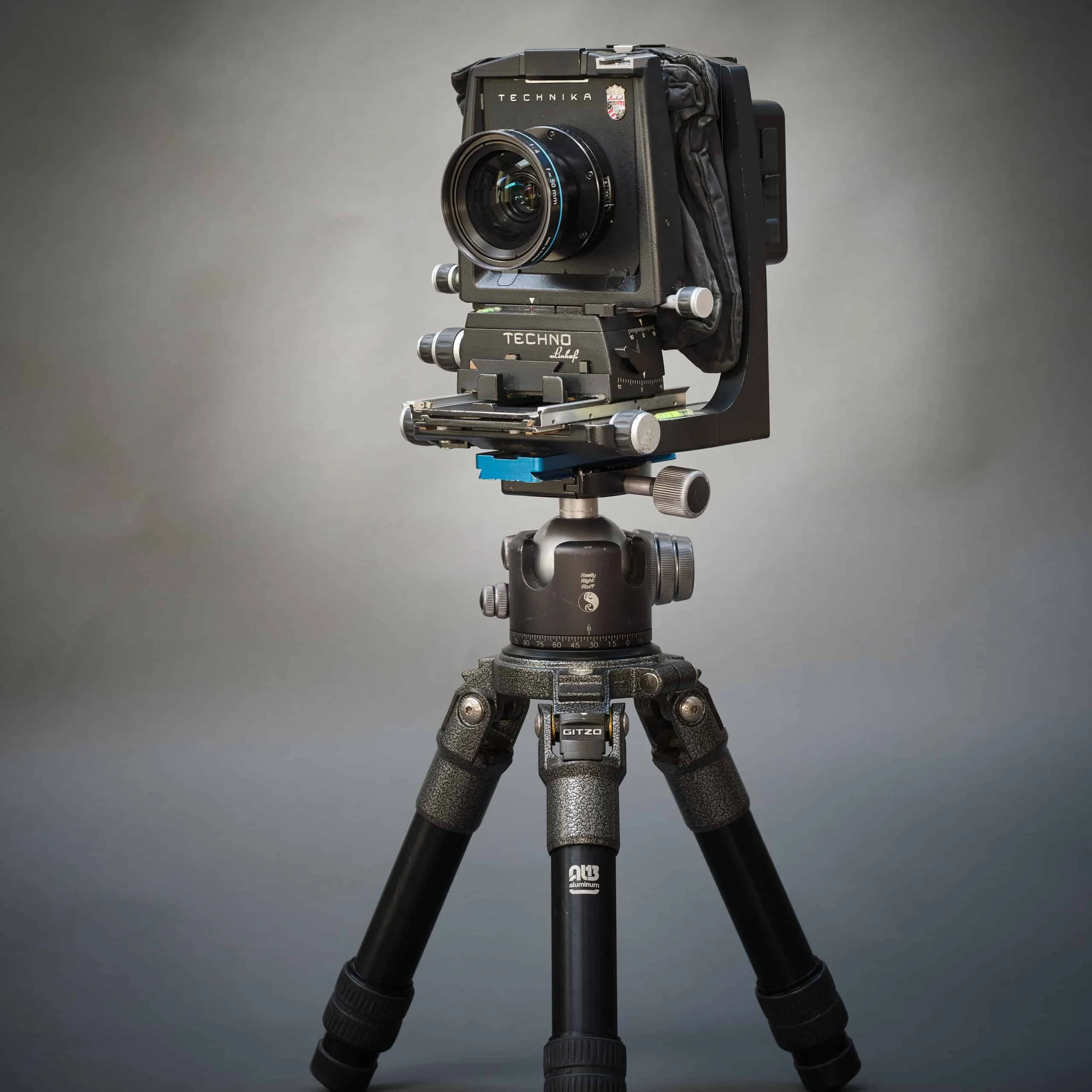 Professional camera mounted on a tripod against a plain grey background.