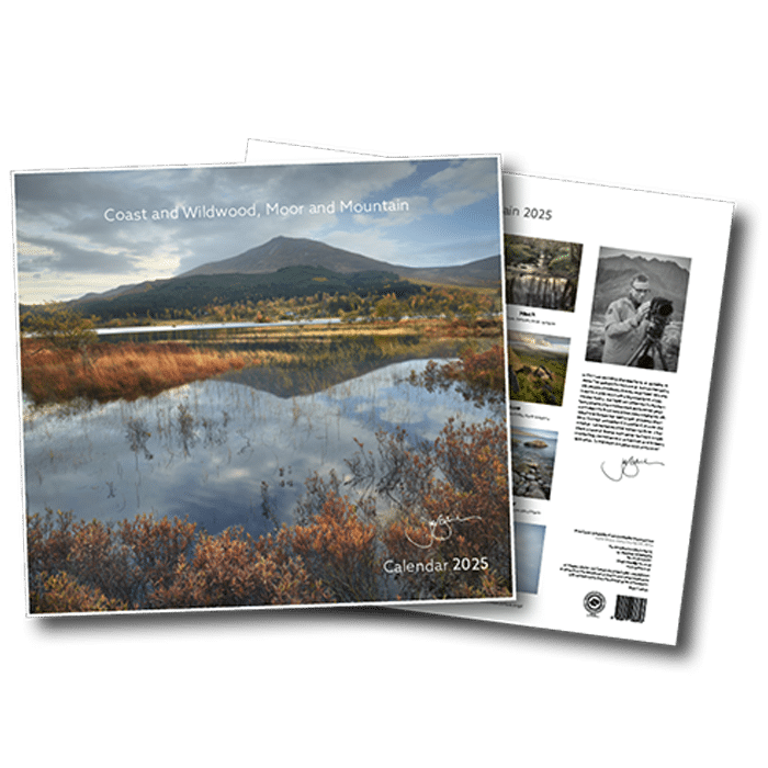 2025 calendar titled 'Coast and Wildwood, Moor and Mountain' featuring a landscape with a mountain, a body of water, and autumn foliage.