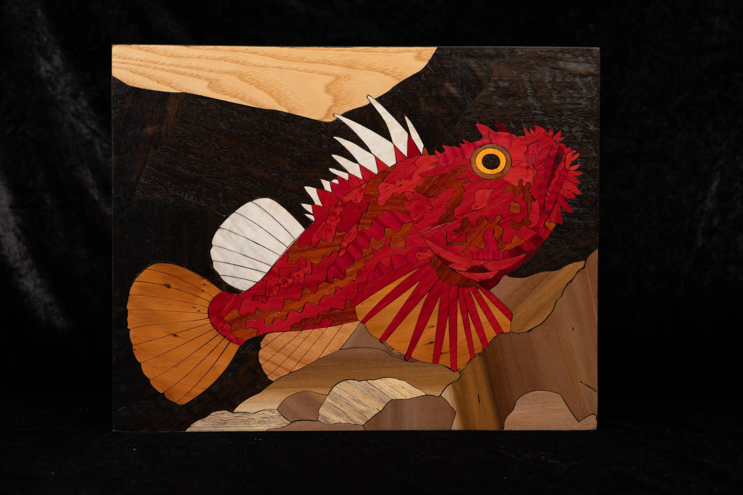 Une pièce d'art en bois représentant un dragon rouge avec des ailes, une tête détaillée, un œil jaune et des écailles, sur fond noir.