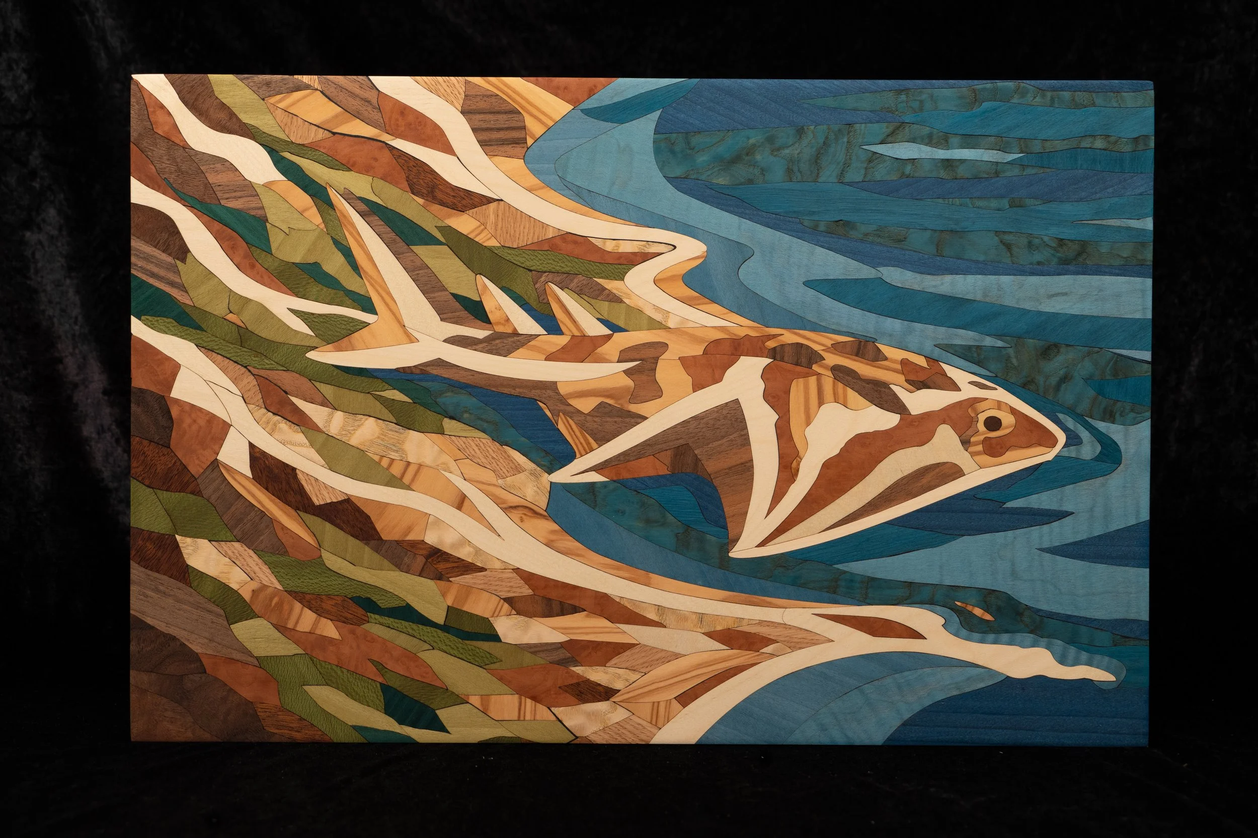 Tableau en bois avec un motif artistique représentant une scène naturelle, avec une rivière bleue et des collines ou montagnes aux couleurs automnales.