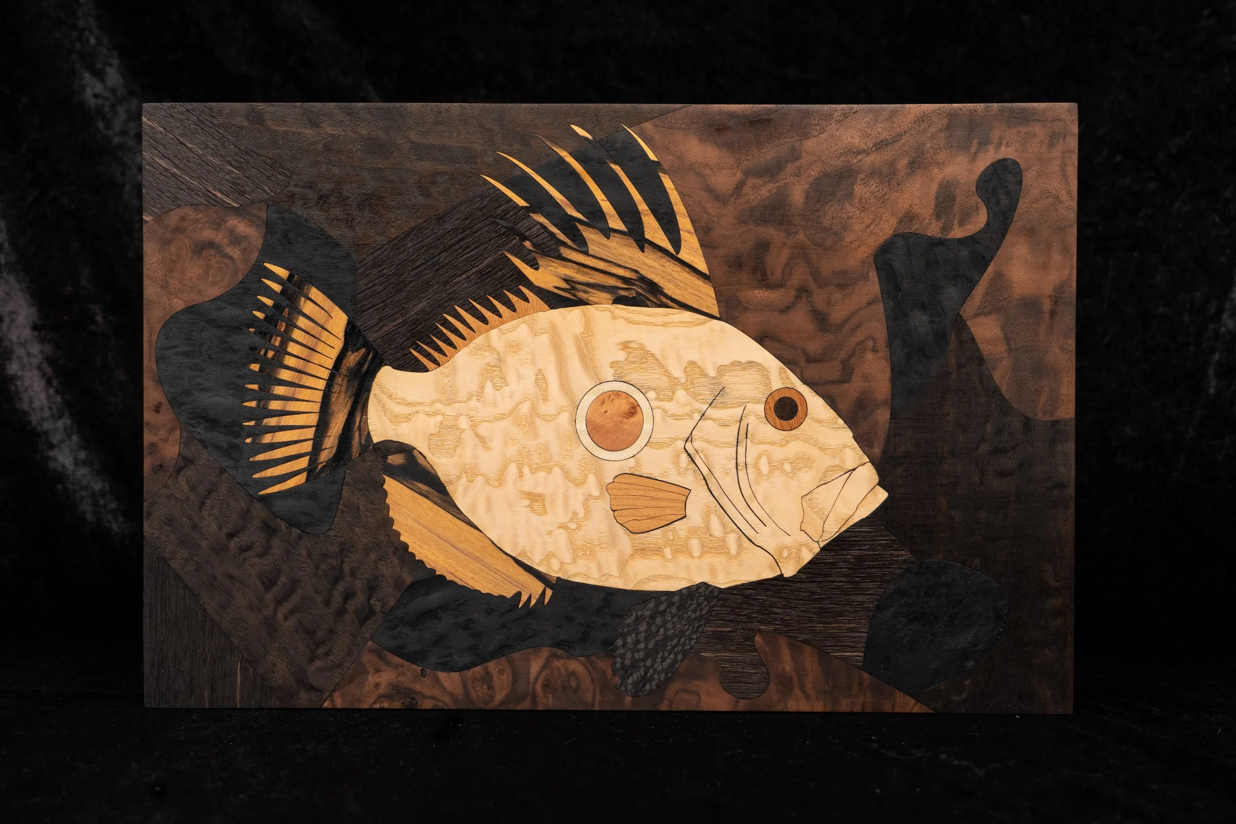 Une œuvre d'art en bois représentant un poisson stylisé avec des détails en noir et en or.