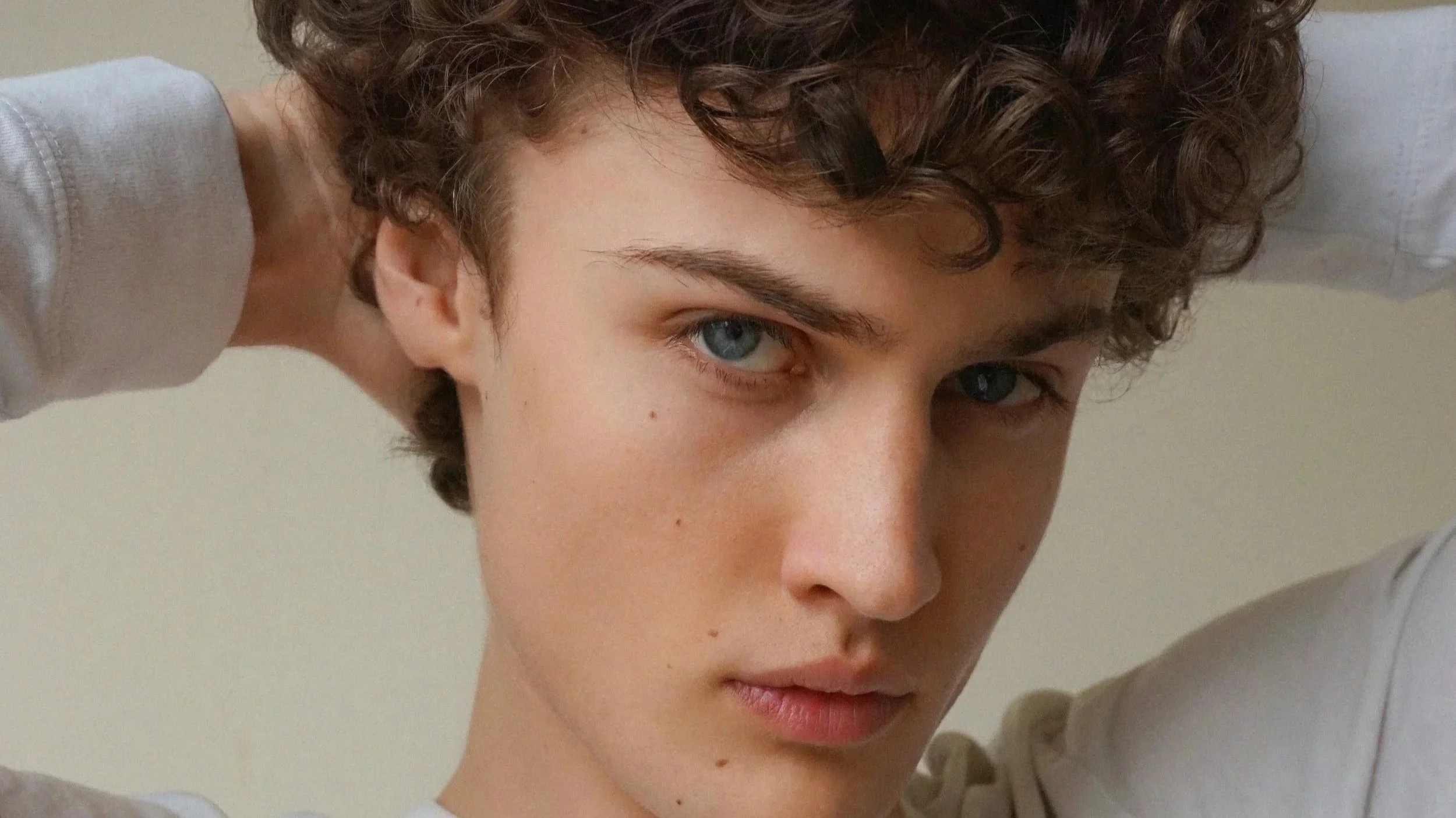 Albert, male Montréal model signed with MTL Models MGMT. Close-up of a young male model with short curly hair, blue eyes, and a serious expression, looking directly at the camera.