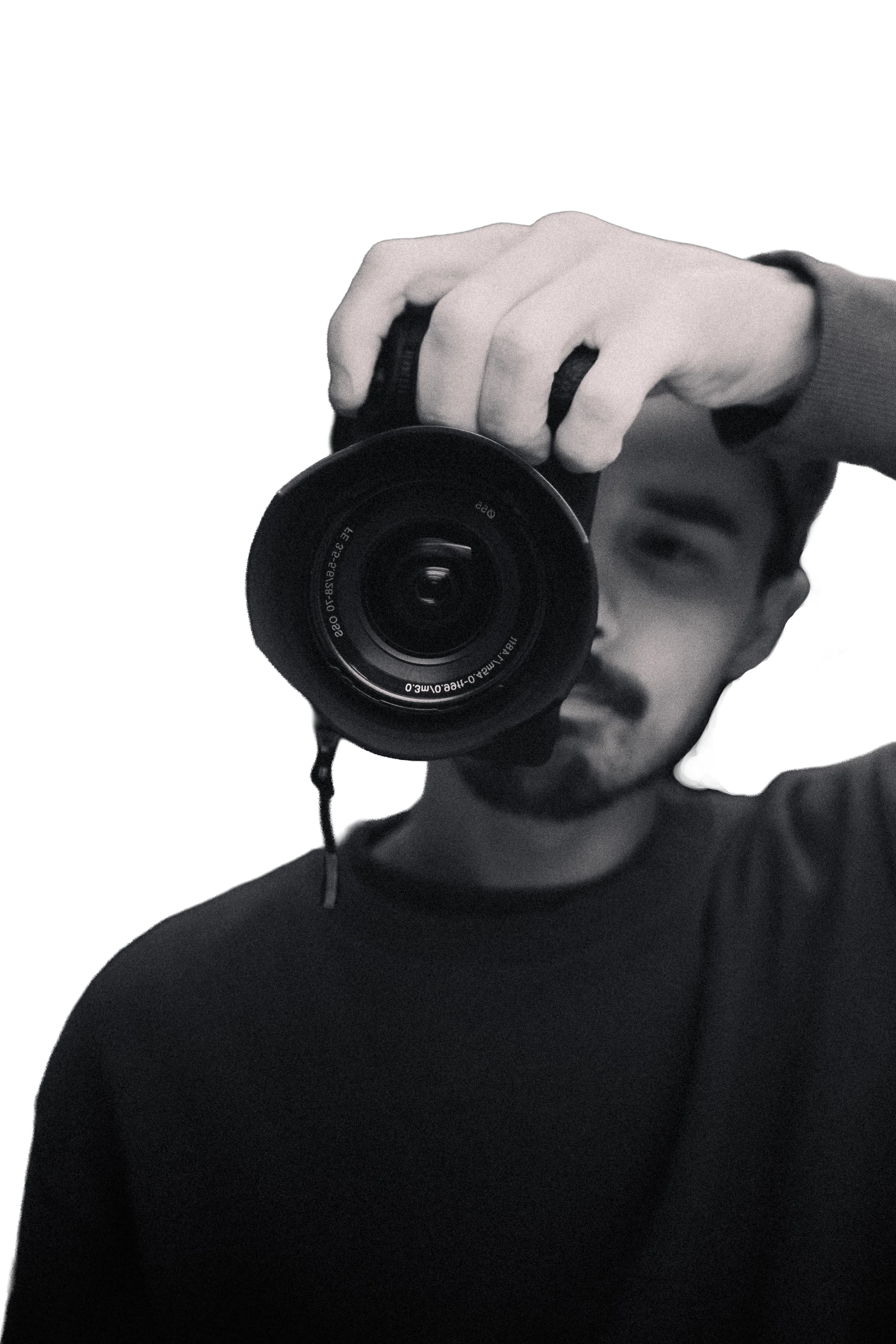 Self portrait of Remi Aleksander holding his camera in front of his face, obscuring half of it