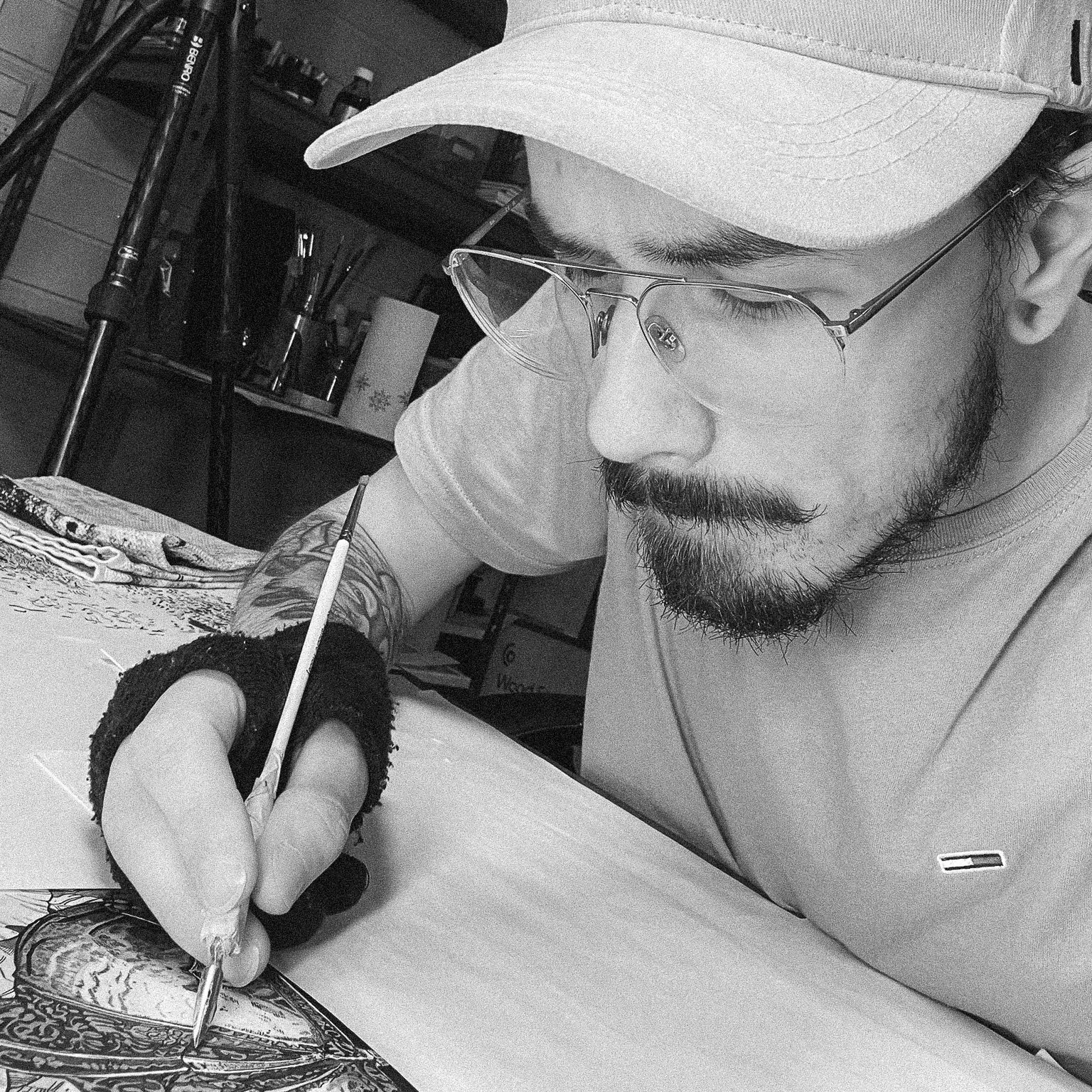 Black and white selfie of Remi Aleksander wearing a caps and glasses as he consentrates on drawing