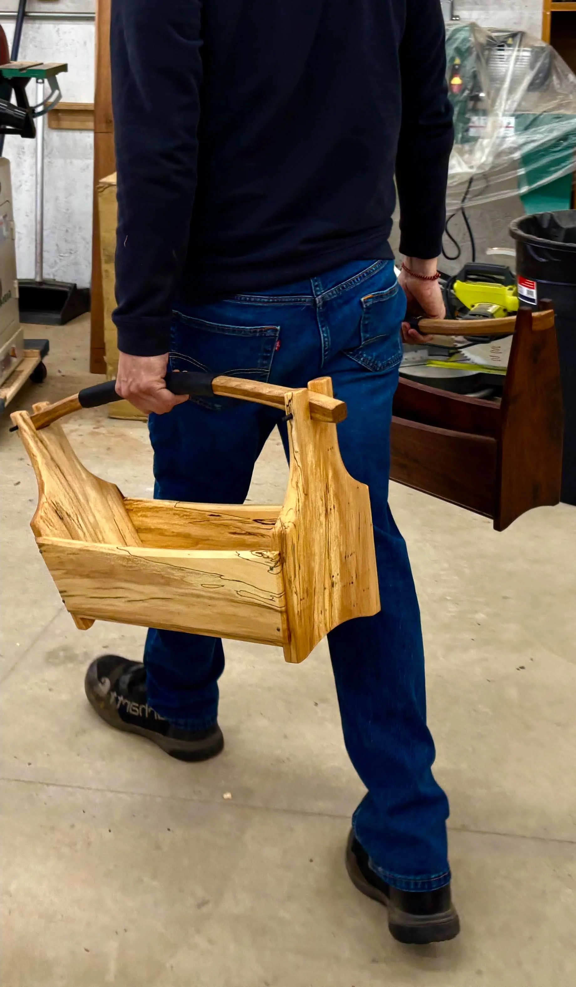 Craftsman Tim Pierce in his workshop carrying a handcrafted wooden tote.