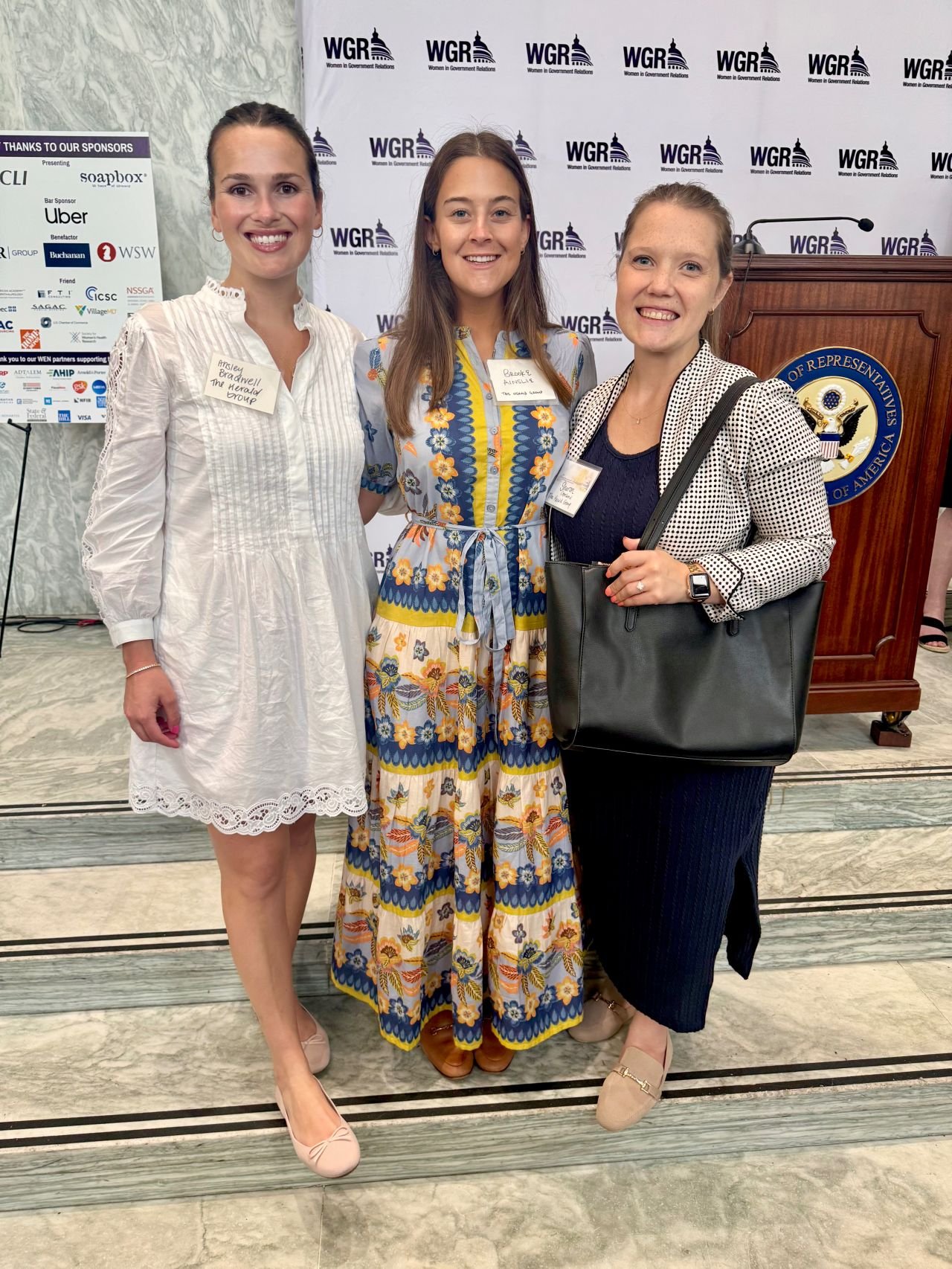 At an event, three women pose together, smiling brightly for the camera, reflecting a moment of happiness and connection.