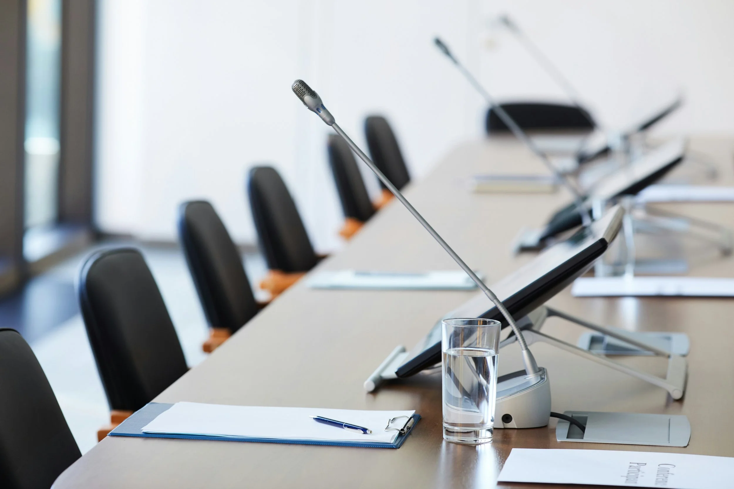 A conference table featuring a laptop and a microphone, set up for a meeting or presentation.
