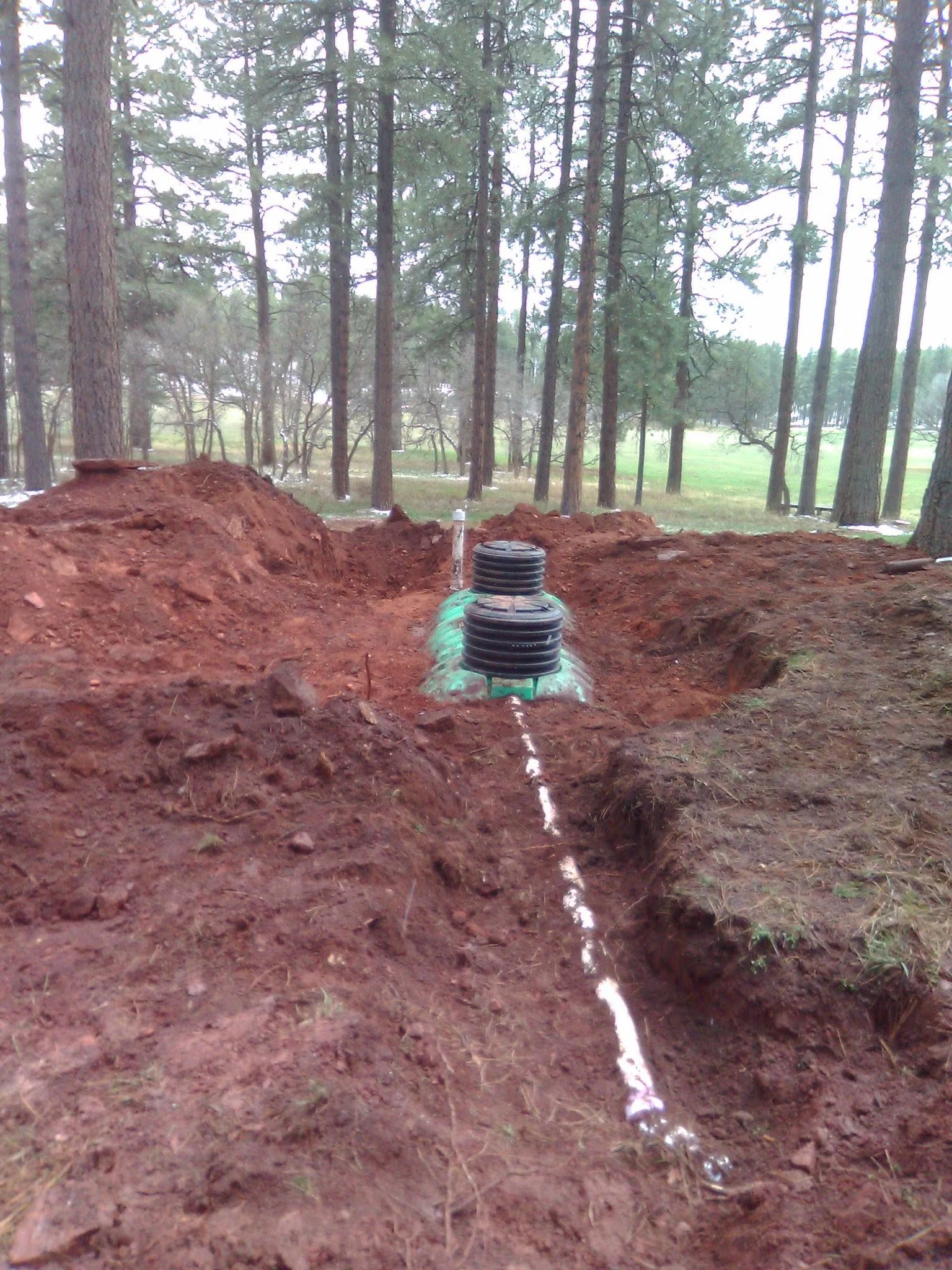The top of a septic tank sticking out of the ground after it's been dug up. 