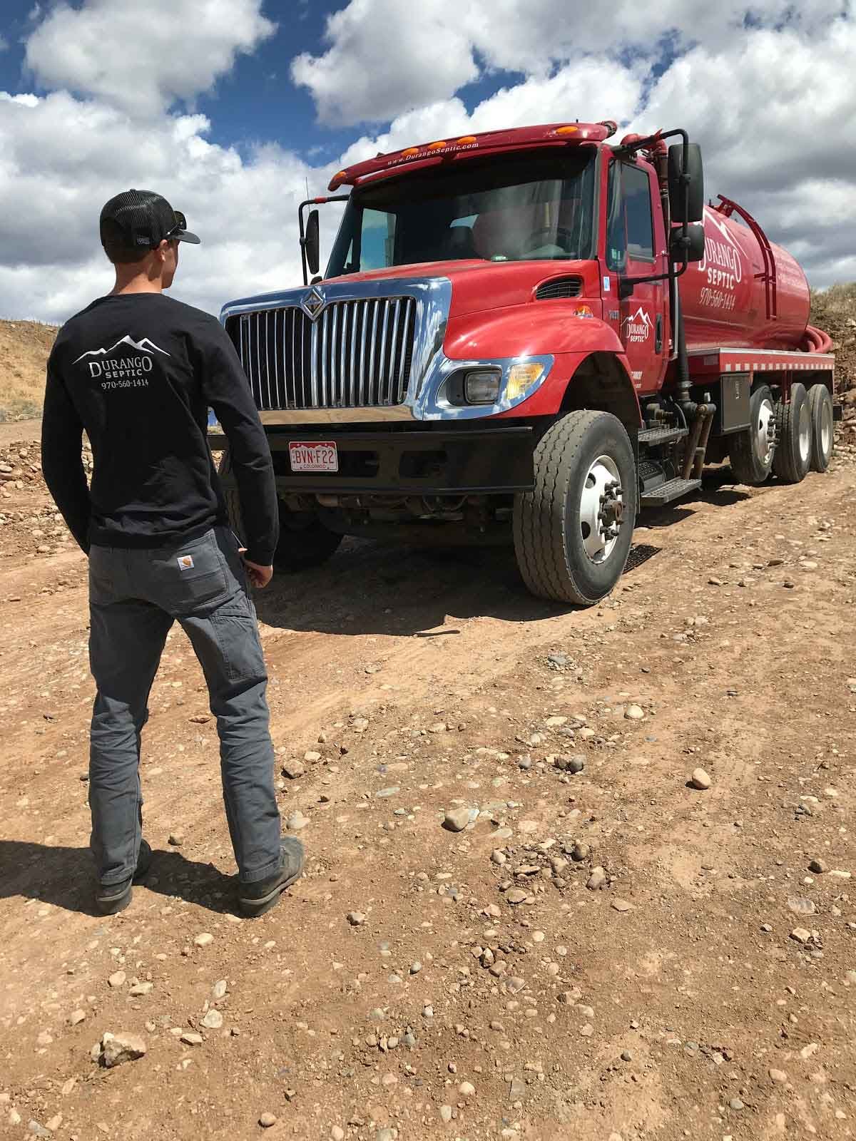 A man standing in front of a red Durango septic tank wearing a Durango septic shirt.