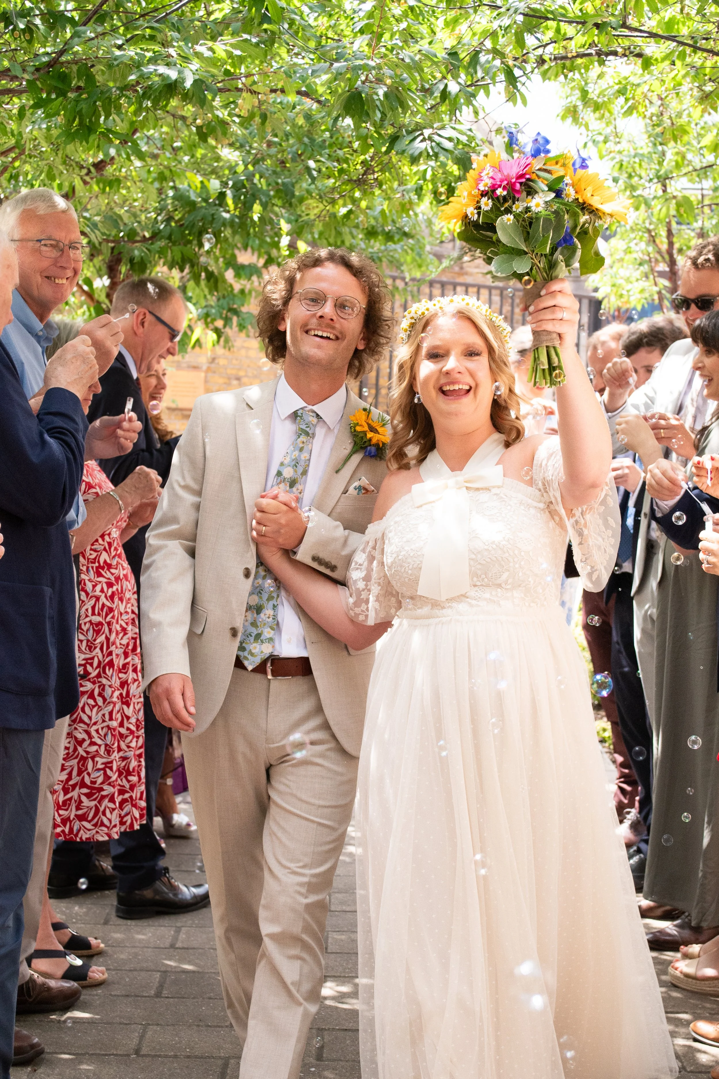 Clients, Clare and Kit walking through a bubble arch after their ceremony