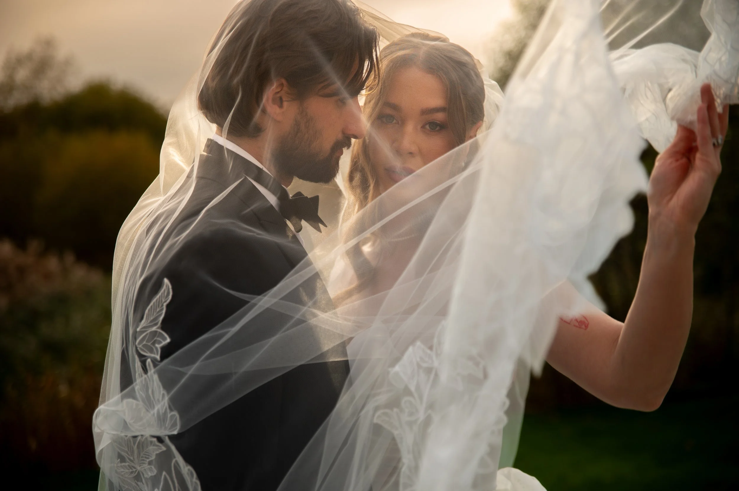 Bride and groom under the veil during golden hour