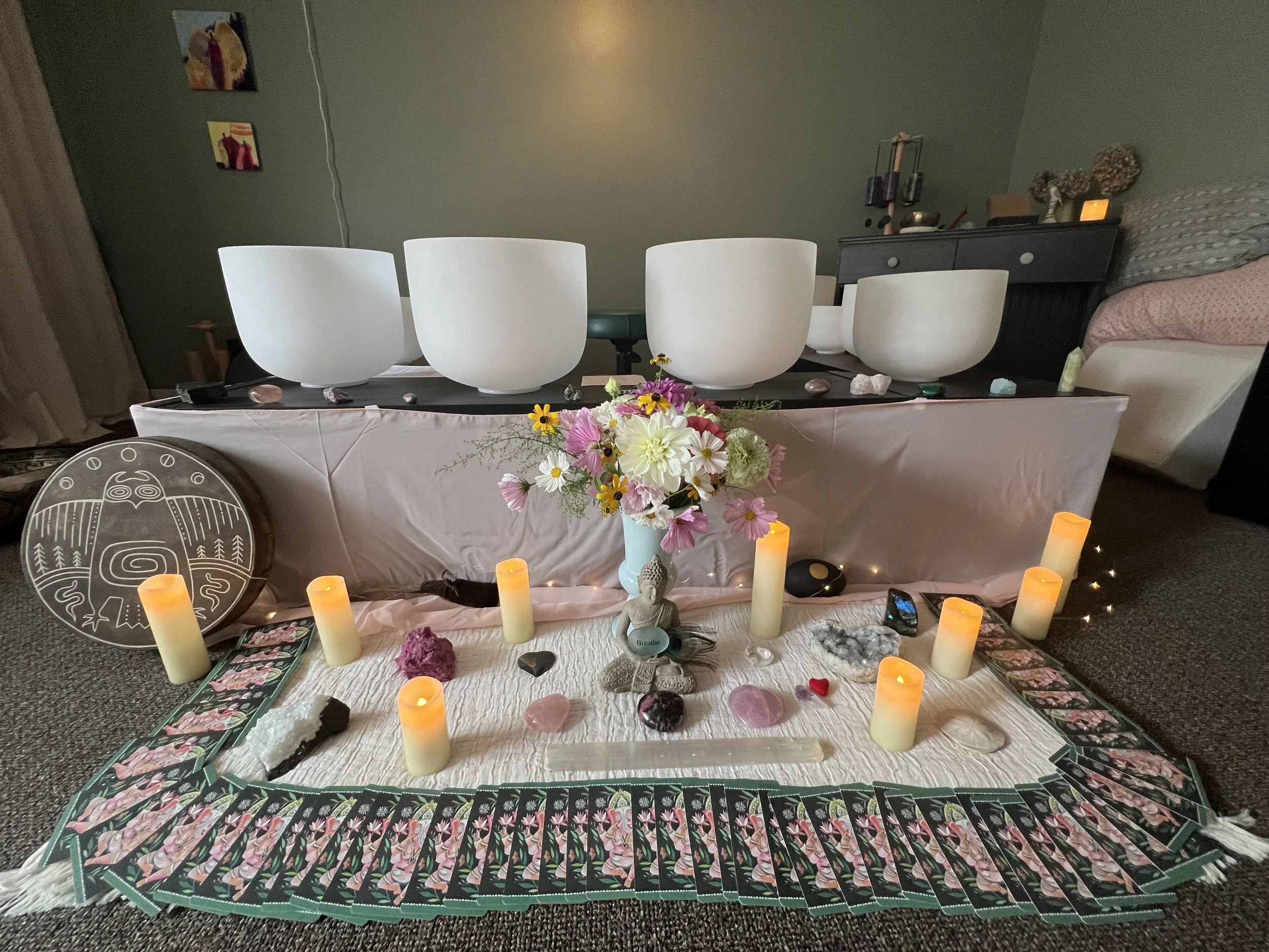 Crystal singing bowls arranged for a restorative sound bath with candles, flowers, and calming ritual elements.