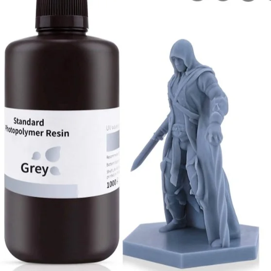 Bottle of gray photopolymer resin next to a gray 3D-printed model of a hooded character with a sword.