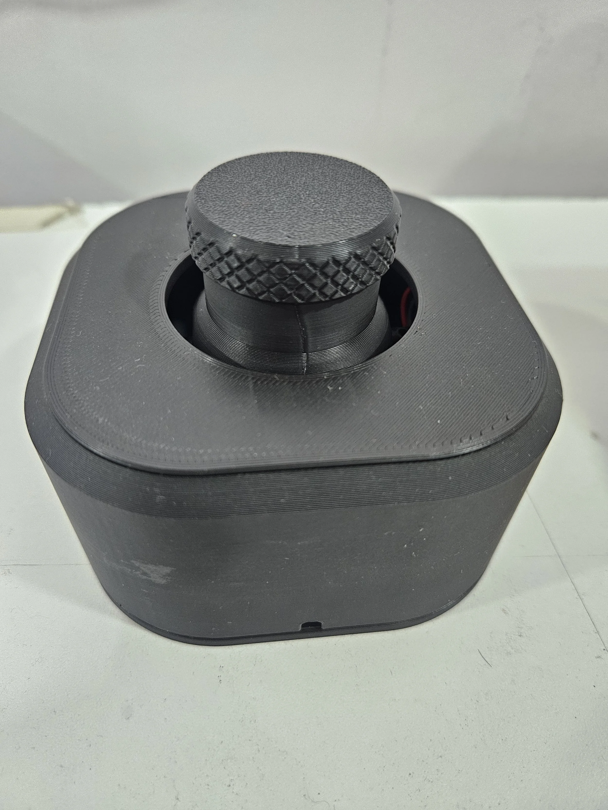 Black portable speaker with rounded top, sitting on a white surface.